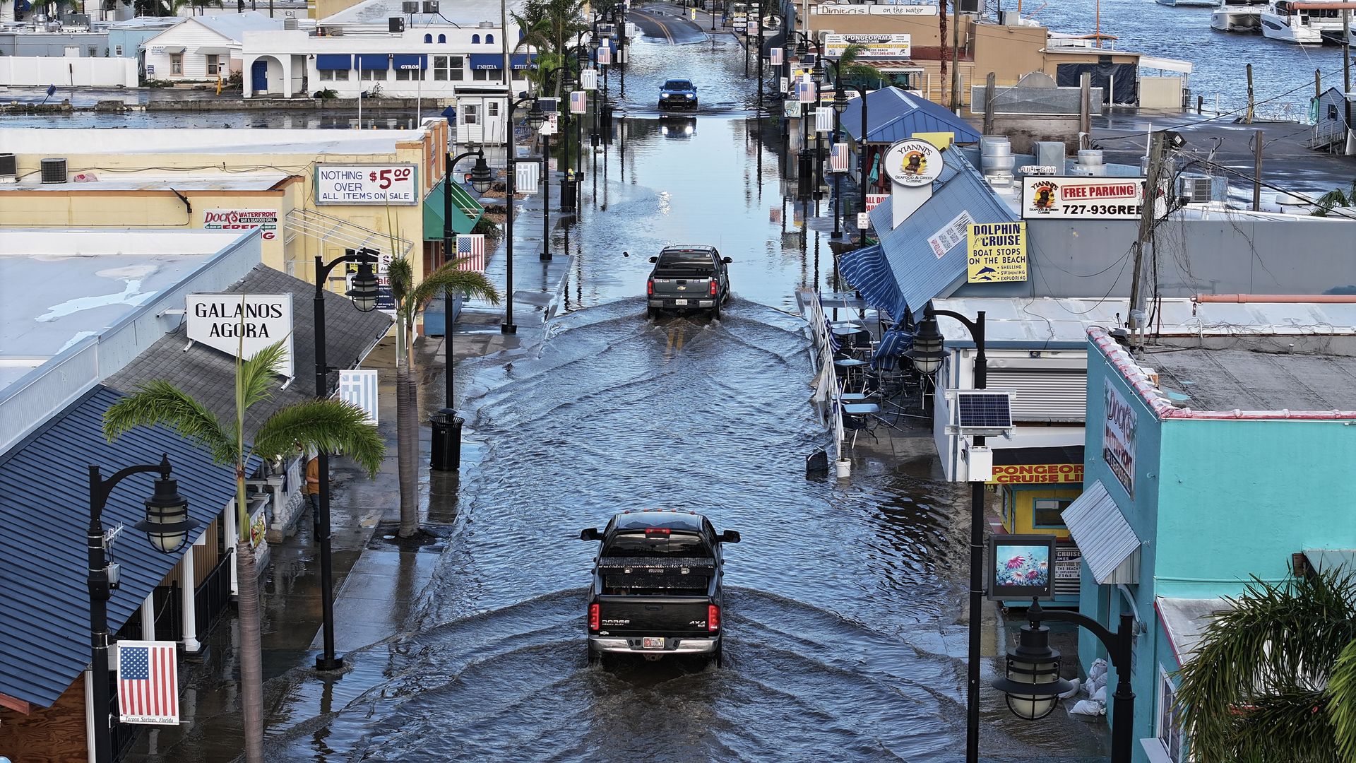 Cars moving through flooded streets in a town.