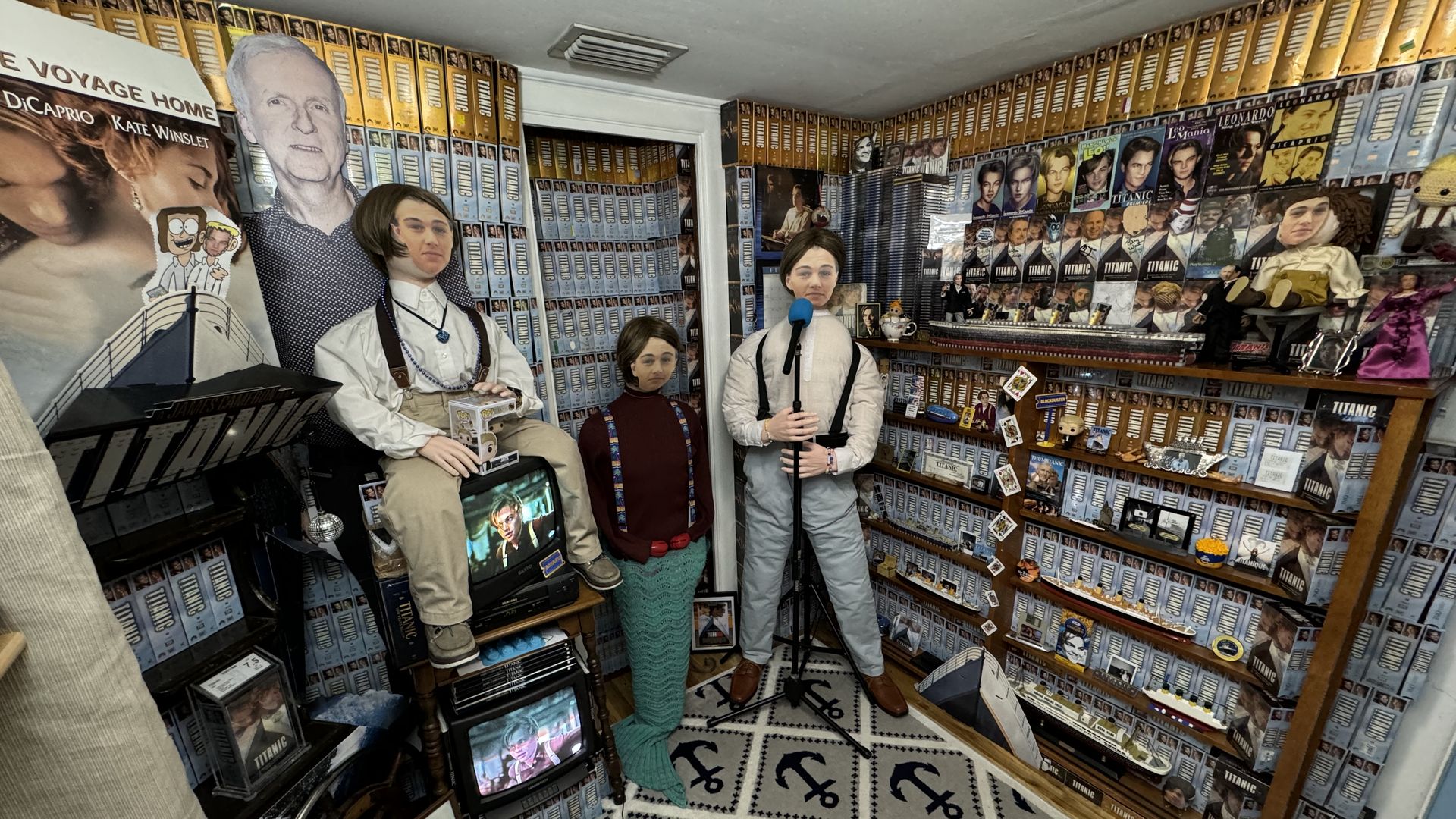 A room lined with VHS tapes of"Titanic" featuring mannequins with Jack Dawson's face and a James Cameron cutout