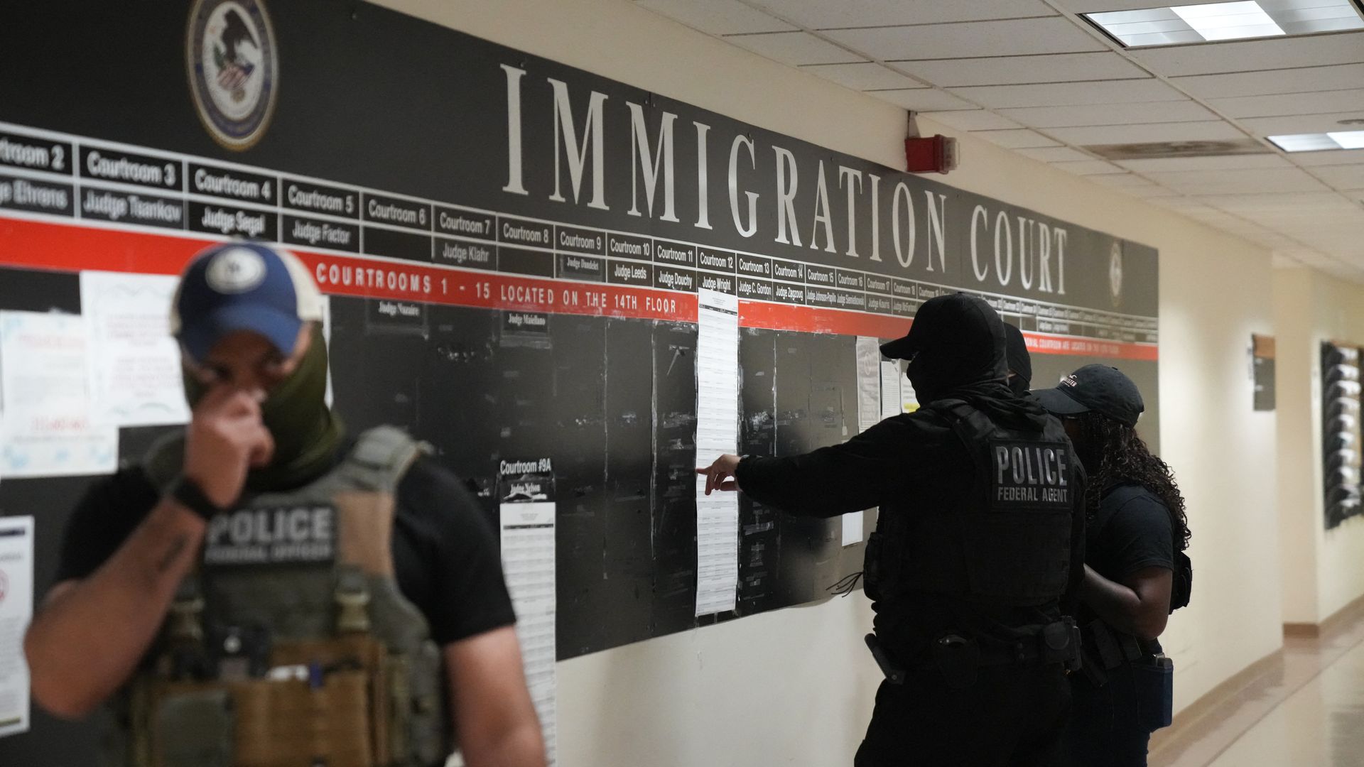 US Immigration and Customs Enforcement (ICE) agents look over lists of names and their hearing times and locations inside the Federal Plaza courthouse before making arrests on June 27, 2025 in New York.