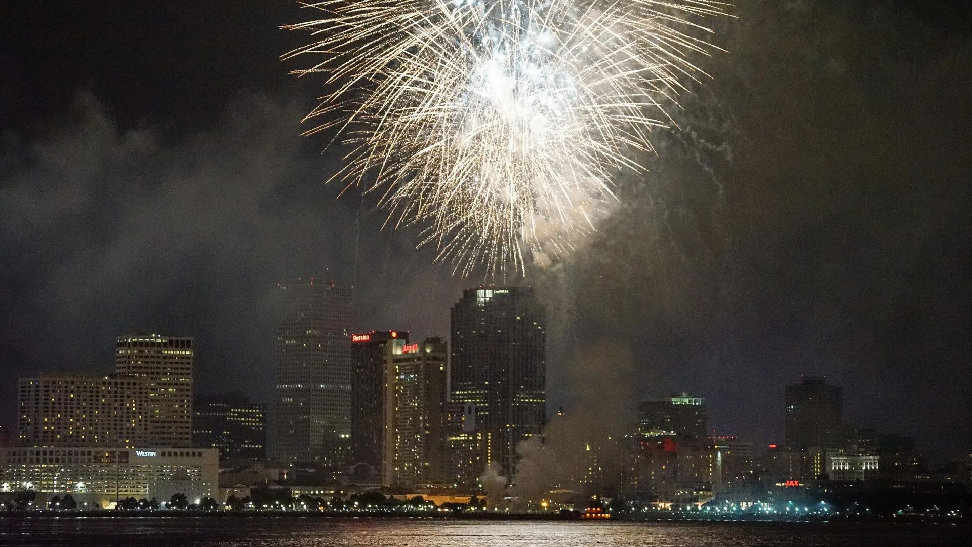 Fireworks explode over a city skyline.