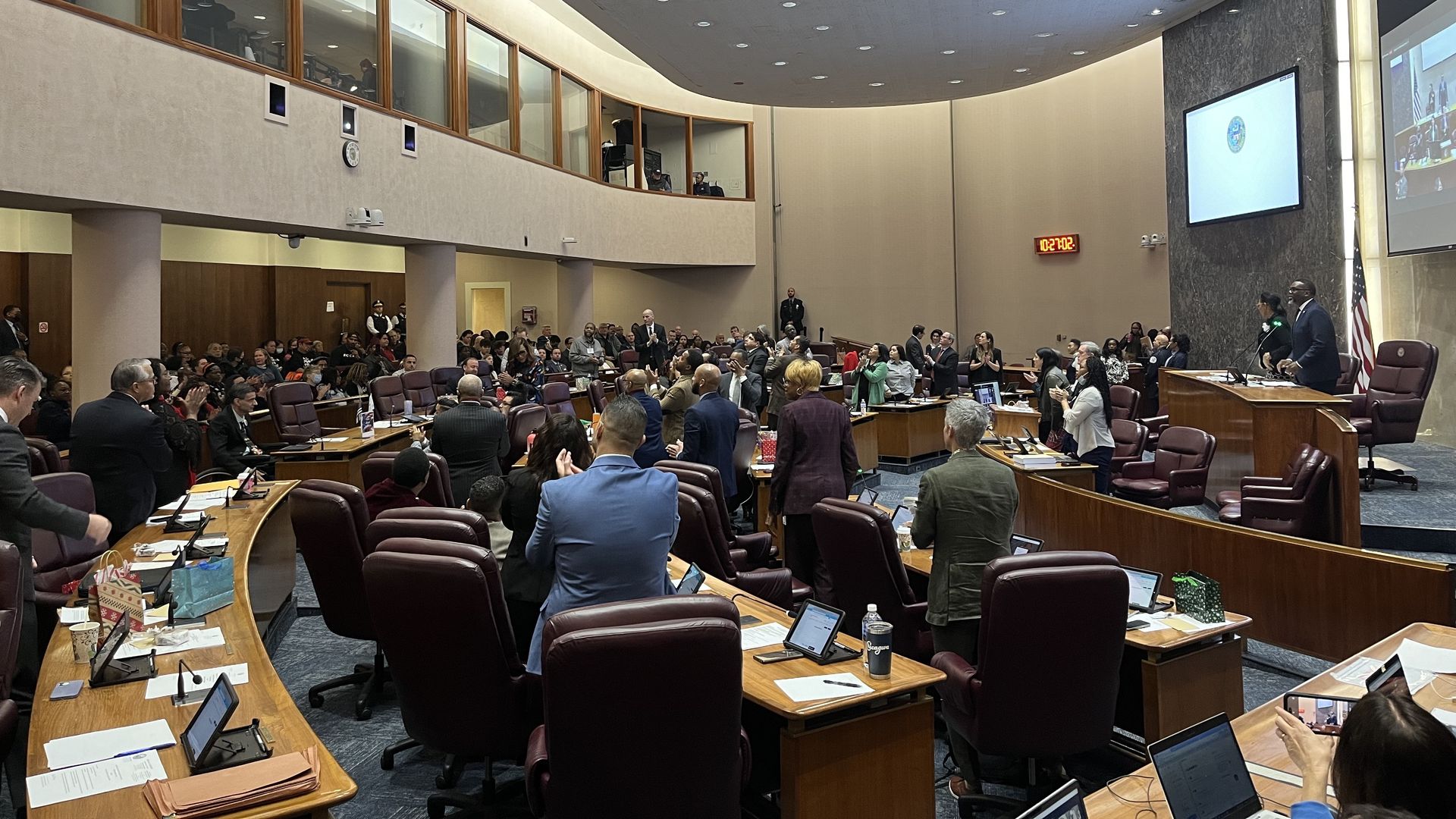 Mayor Brandon Johnson presides over a City Council meeting, with alders standing and clapping from their seats.