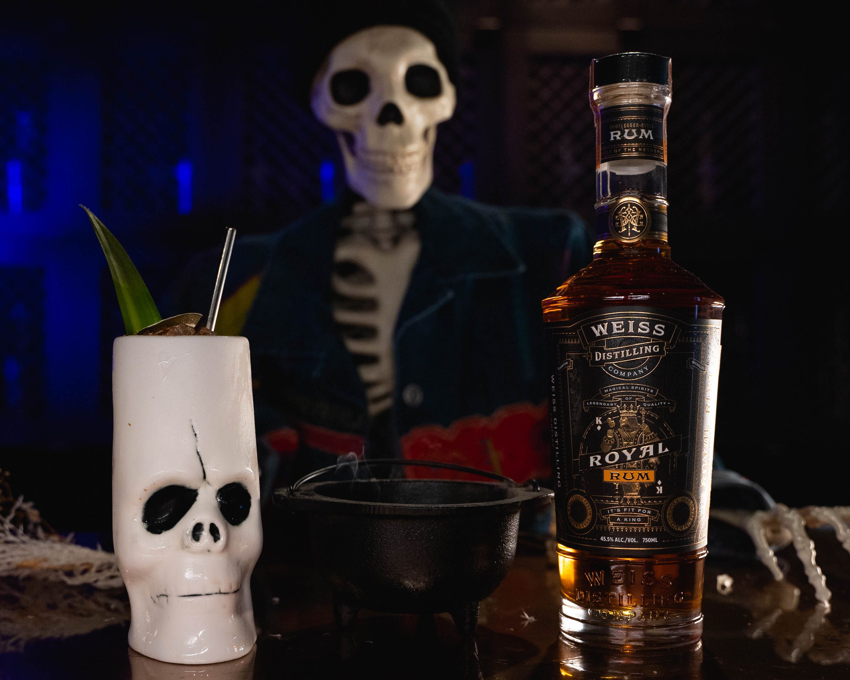 A bottle of liquor next to a skull-shaped glass.