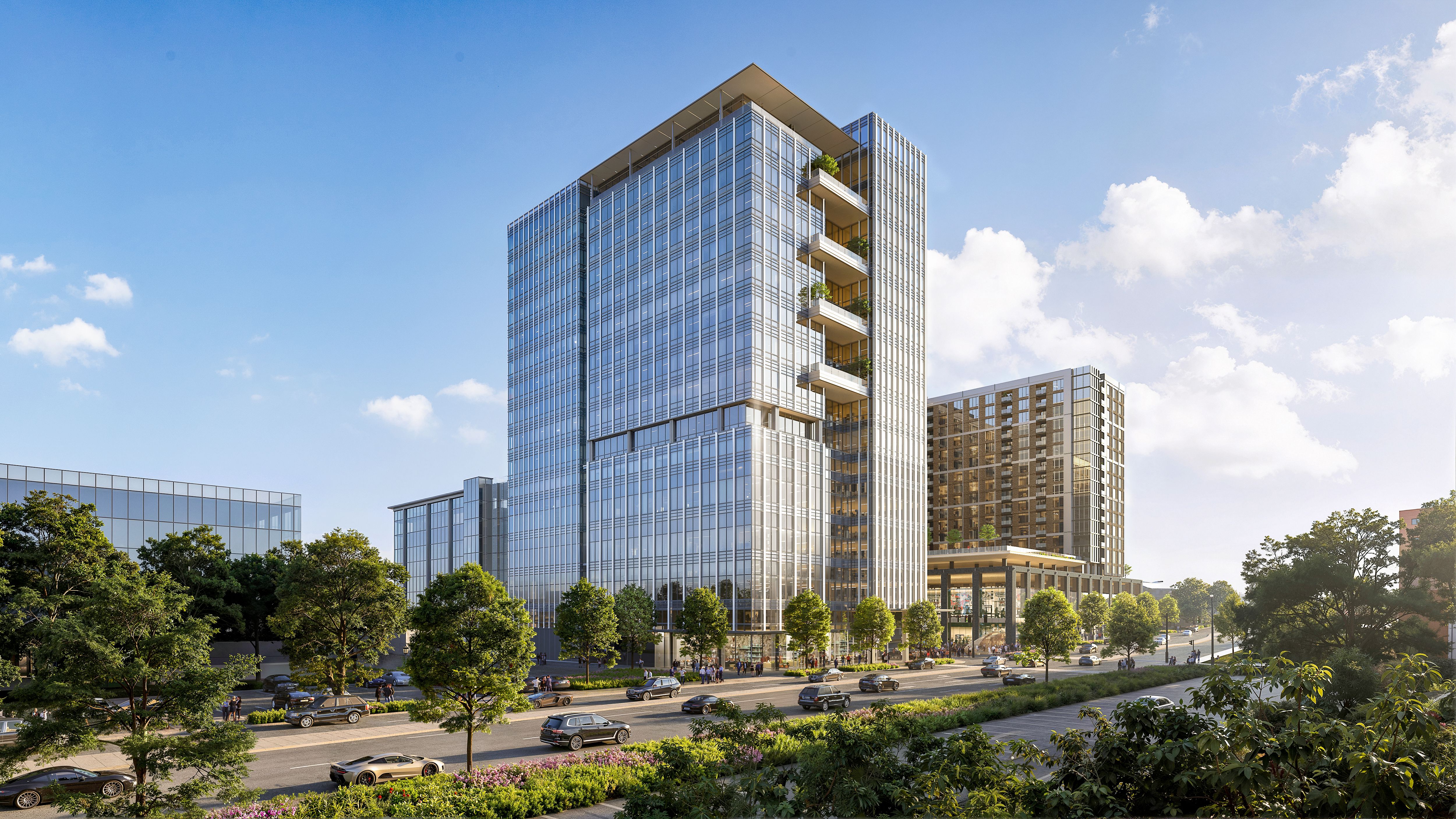 Modern glass office tower with staggered balconies and greenery, reflecting the blue sky. Foreground shows a tree-lined street with cars and other glass buildings nearby.