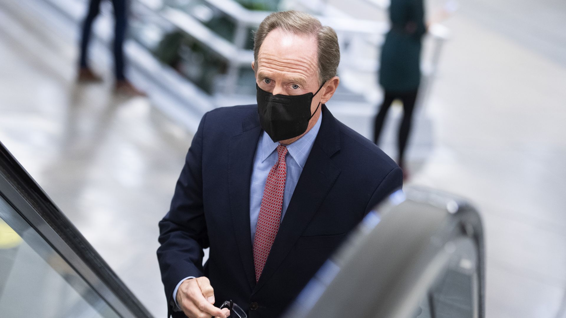 Pat Toomey wears a face mask while walking on an escalator
