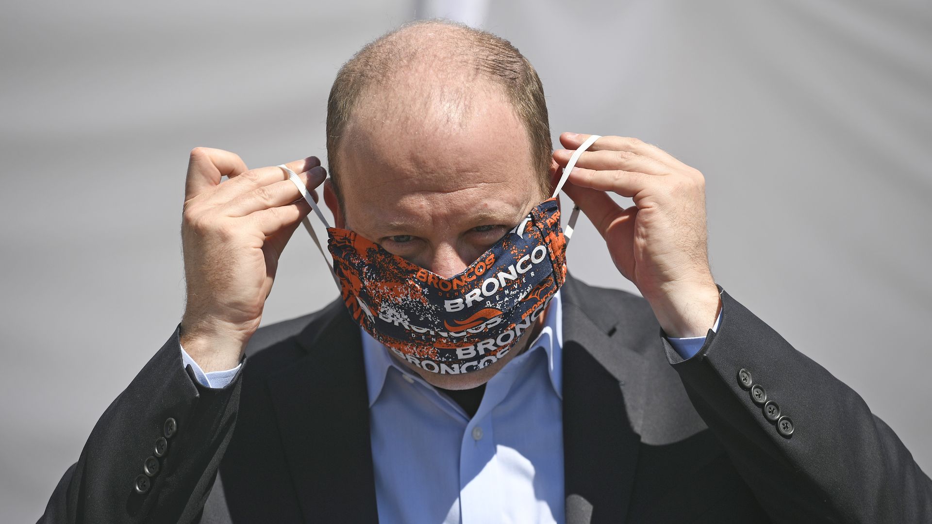 Colorado Gov. Jared Polis adjusts his face mask. 