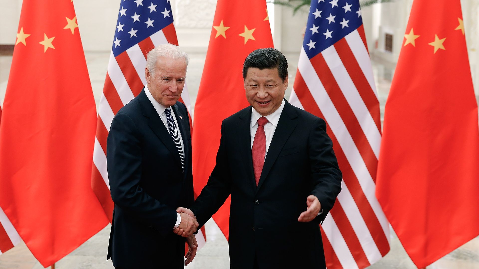Photo of Joe Biden shaking hands with Xi Jinping with Chinese and American flags in the background