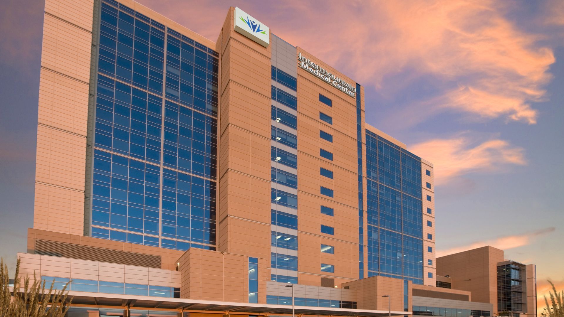 A beige Intermountain hospital with a sunset sky in the background.