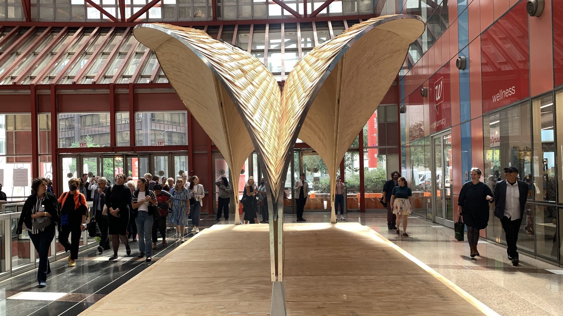 V-shaped light-colored wood structure in front of red beams.