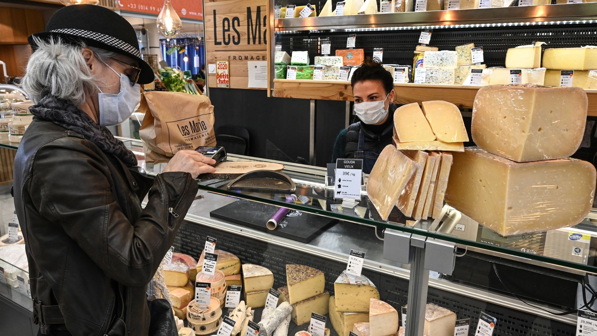 A woman wearing a protective face mask buys cheese at a store in the center of Montpellier, south of France, on March 25