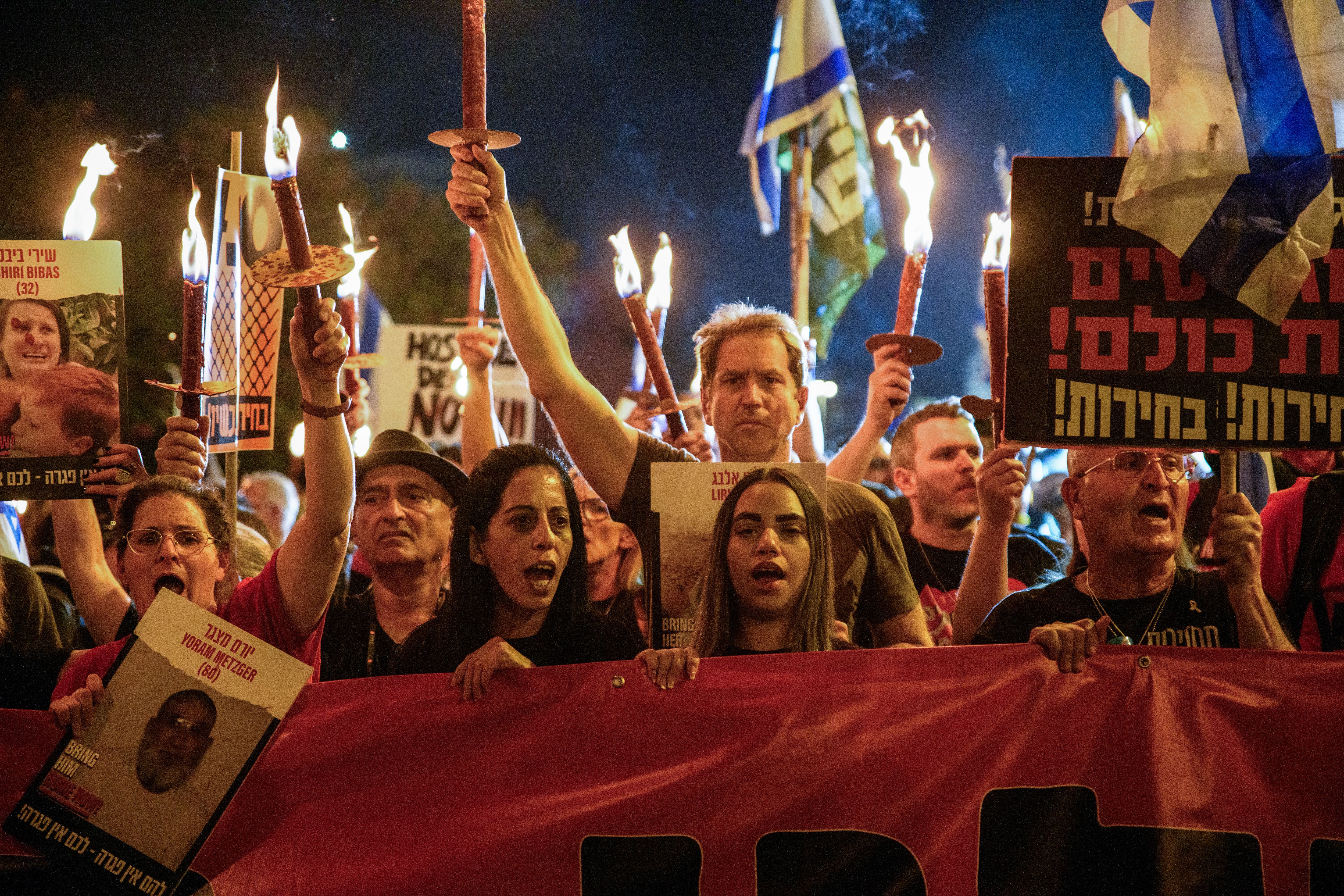 A group of Israeli protestors holding candles and signs. 