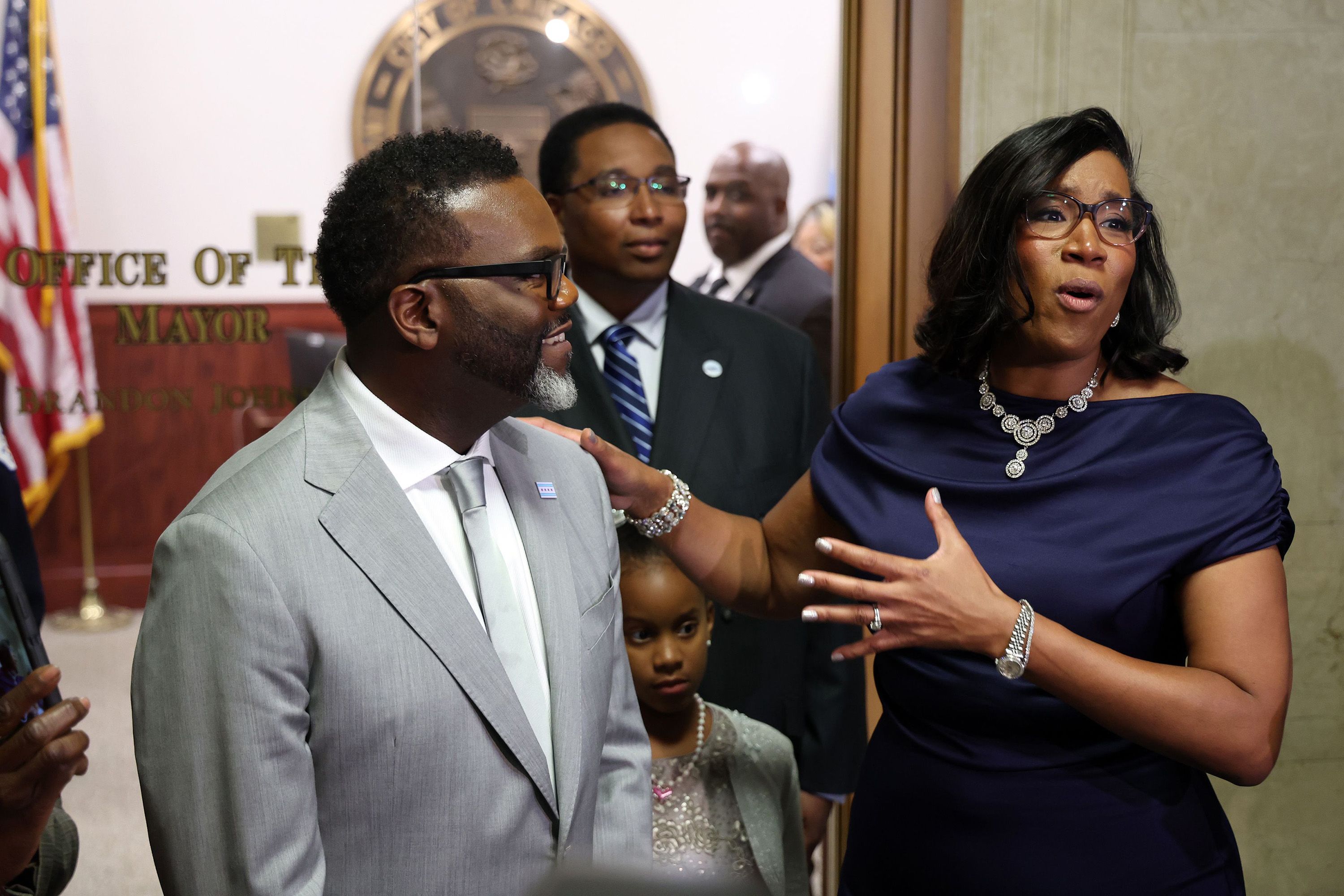 Photo of a man and woman talking to reporters outside an office door
