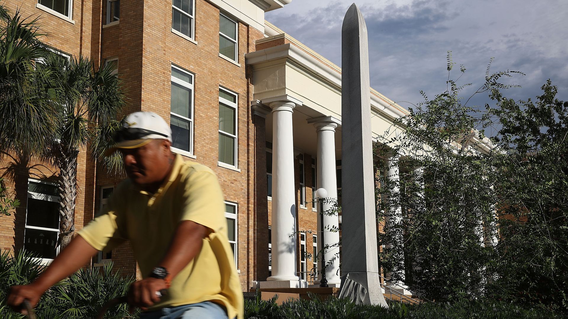 A bicyclist in a yellow polo and jeans rides past the granite obelisk commemorating Confederate soldiers in Bradenton in 2017.
