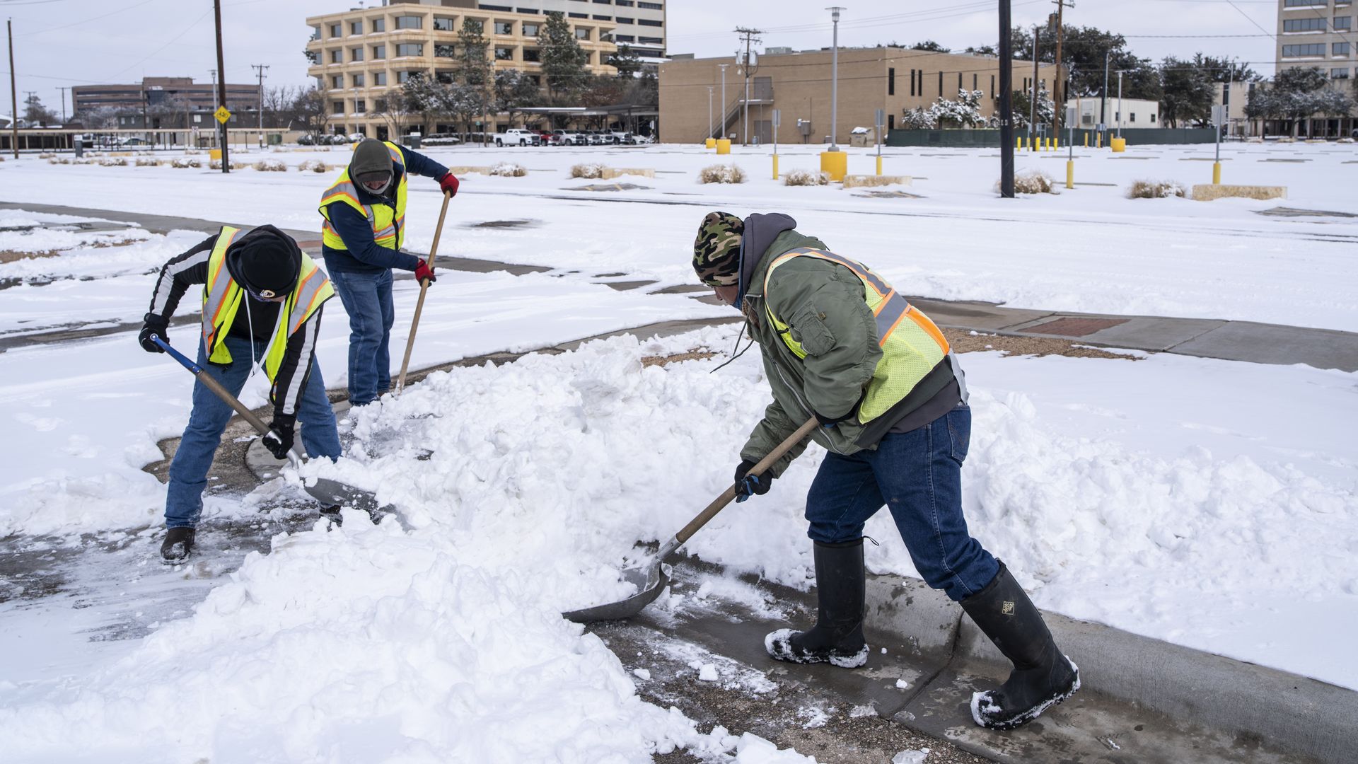Workers clear snow from a parking lot in Midland, Texas, U.S, on Monday, Feb. 15