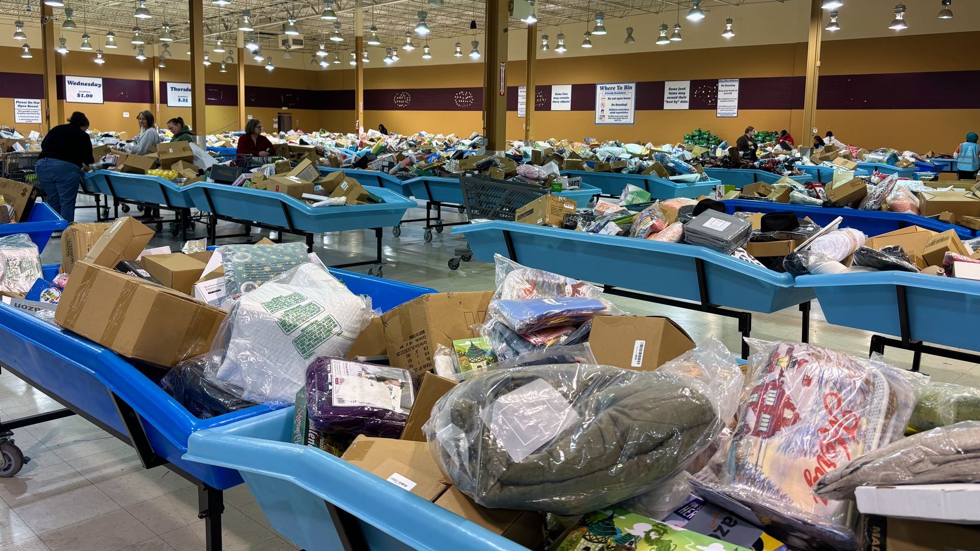 Rows of blue plastic bins containing merchandise in cardboard boxes and plastic bags.