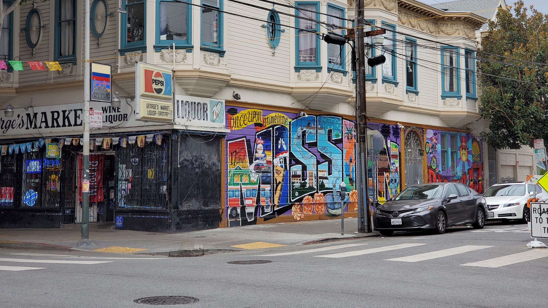 Photo of a street intersection with a colorful mural of the word "Mission"