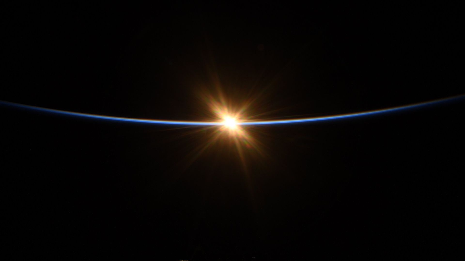 A small spot of sunlight appearing on the blue limb of the Earth from the International Space Station.