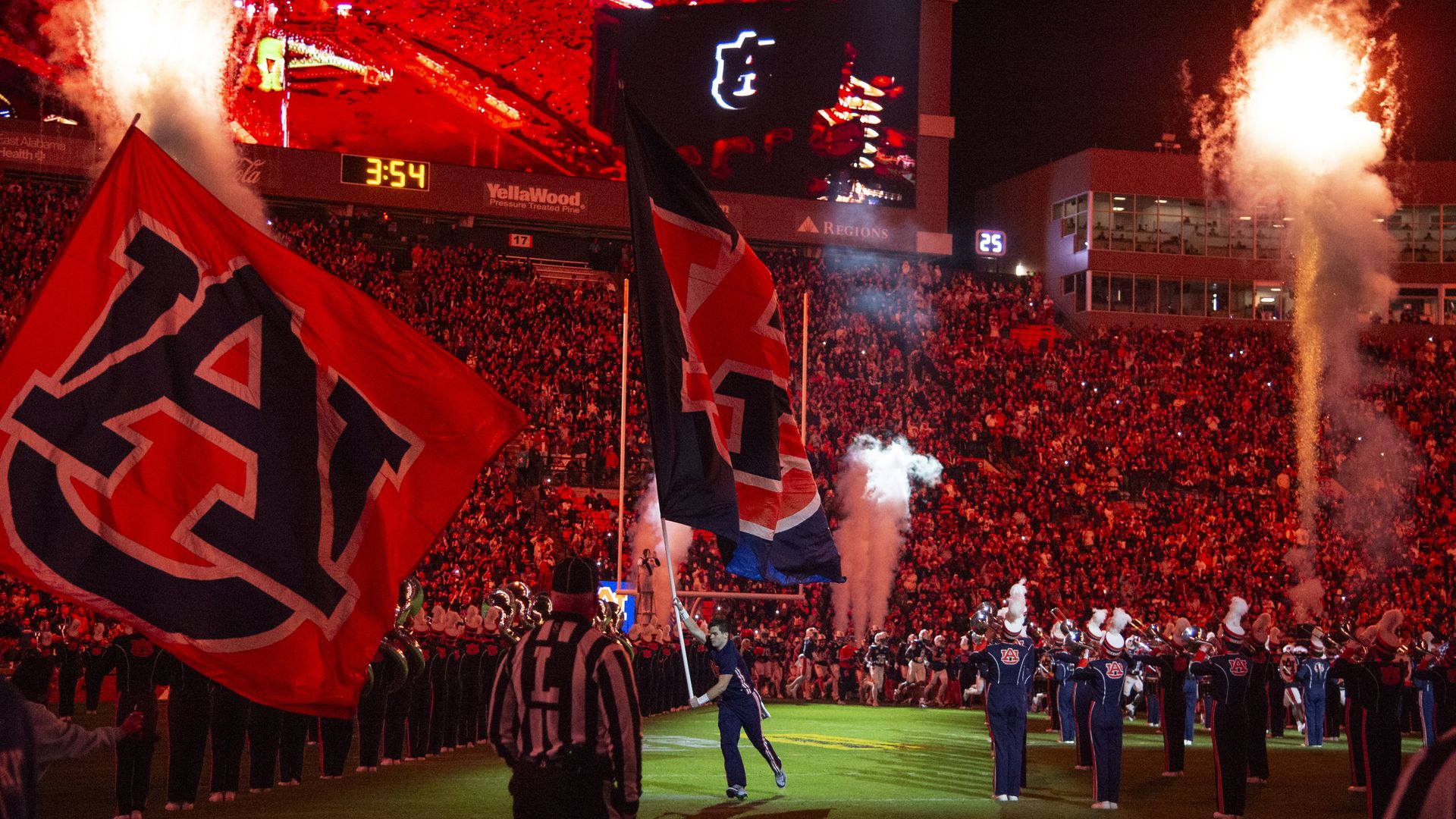 A full Jordan-Hare Stadium at Auburn, Alabama, is shown at night, with fireworks exploding and the marching band on the field.