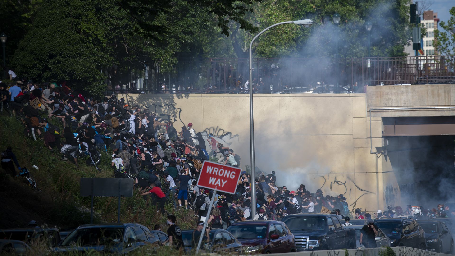 Protesters demonstrating on I-676 run up a hill after being shot by tear gas by police on June 1, 2020.
