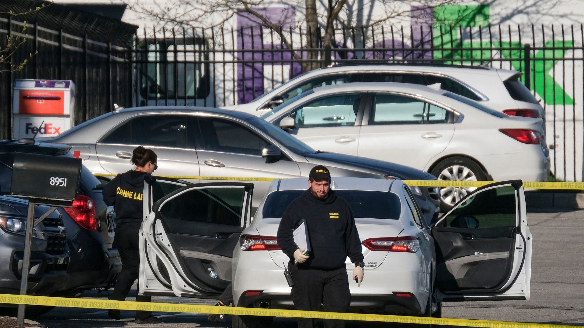 An investigator walks behind yellow crime scene tape at the FedEx warehouse in Indianapolis. 