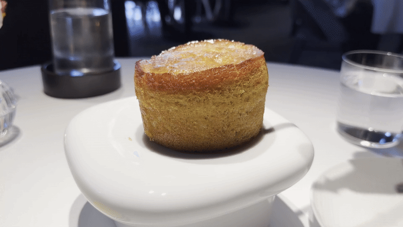 A steaming wedge is taken out of a small circular loaf of cornbread.