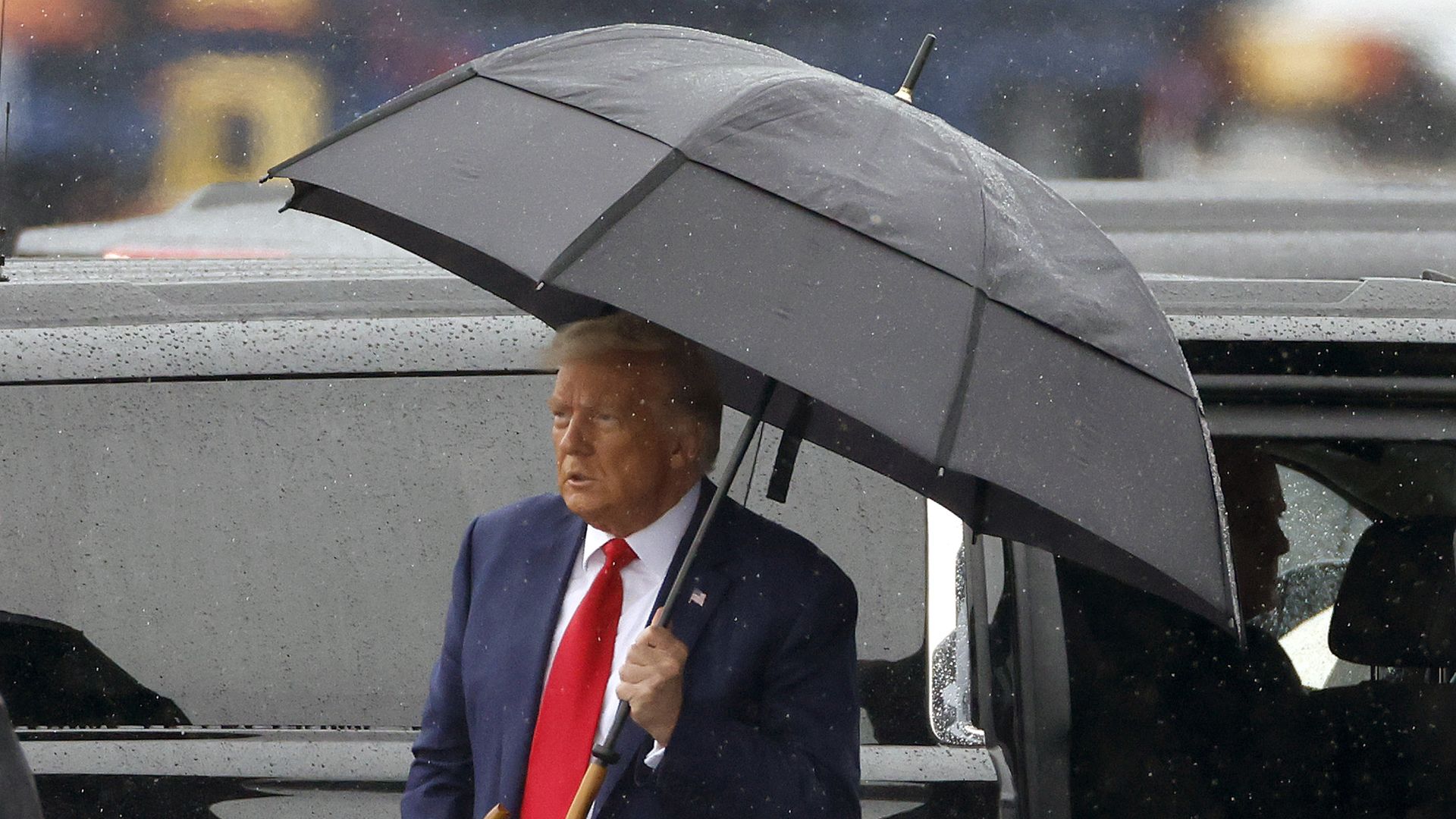 Former U.S. President Donald Trump holds an umbrella as he arrives at Reagan National Airport following an arraignment in a Washington, D.C. court on August 3, 2023 in Arlington, Virginia. 