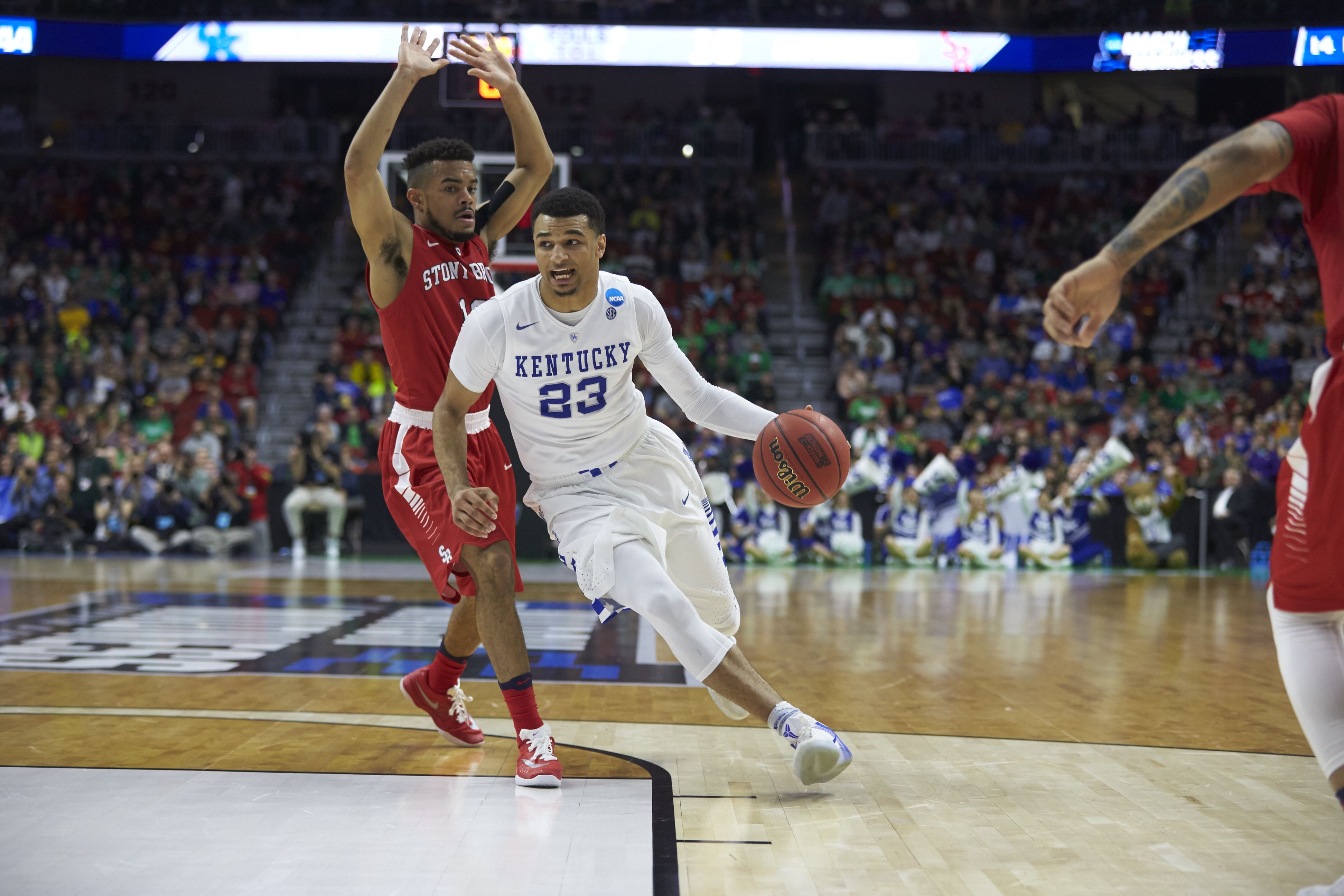 A man handles a basketball while driving forward.