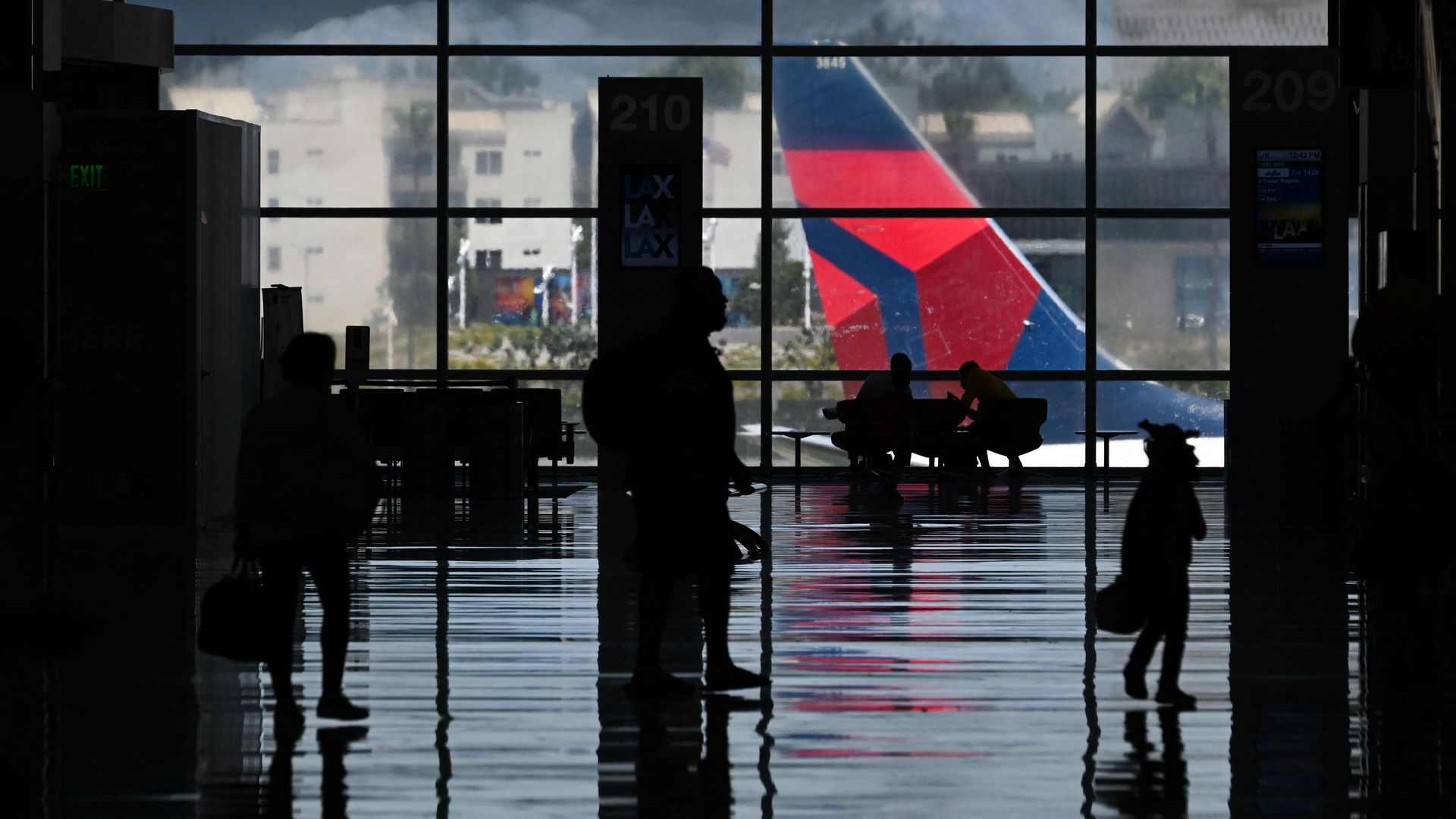Passengers carry baggage as they walk to flights in the West Gates terminal expansion at Los Angeles International Airport (LAX) in Los Angeles, California, on August 10, 2022.