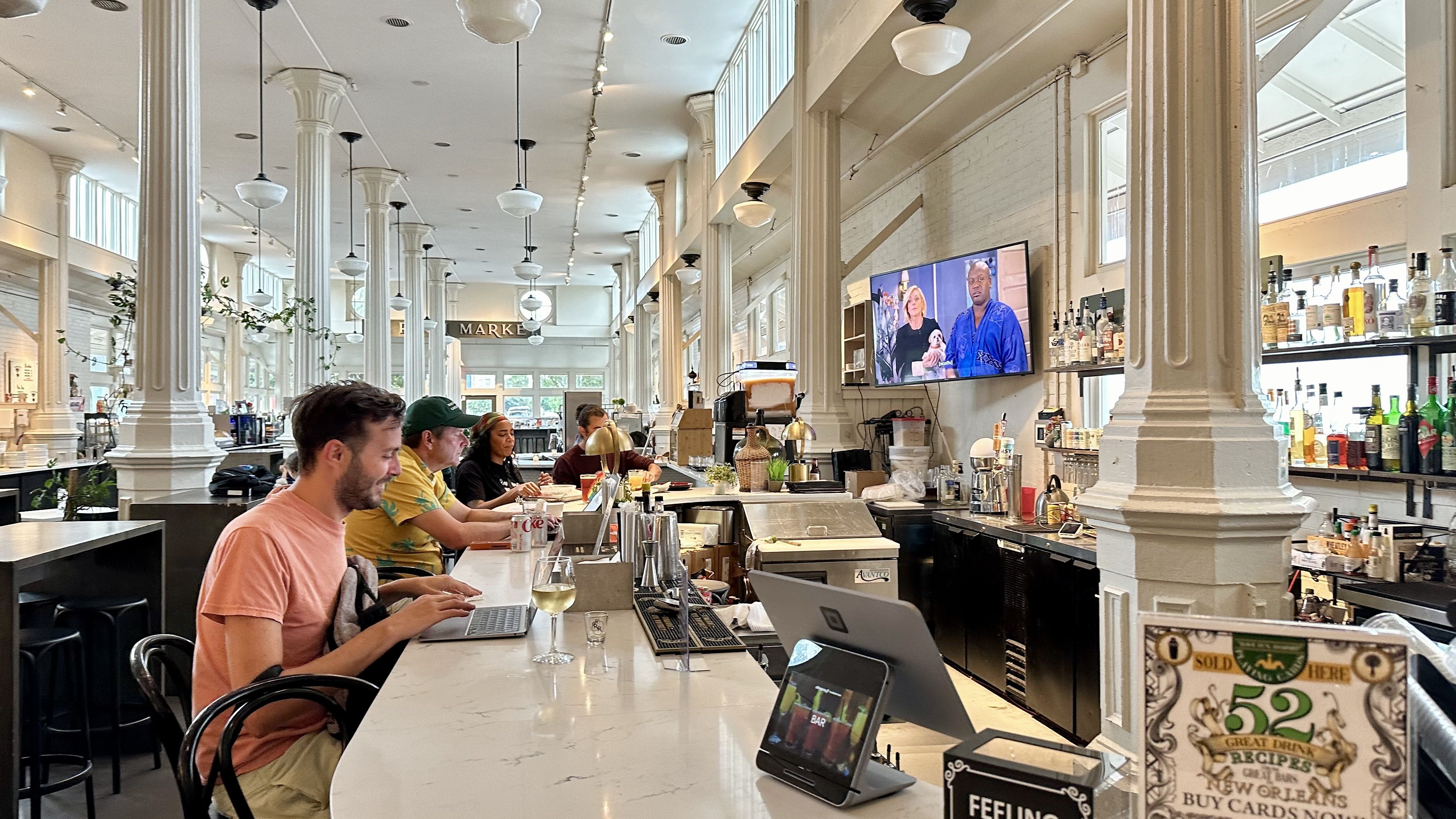 Photo shows people sitting at a bar inside the St. Roch Market.