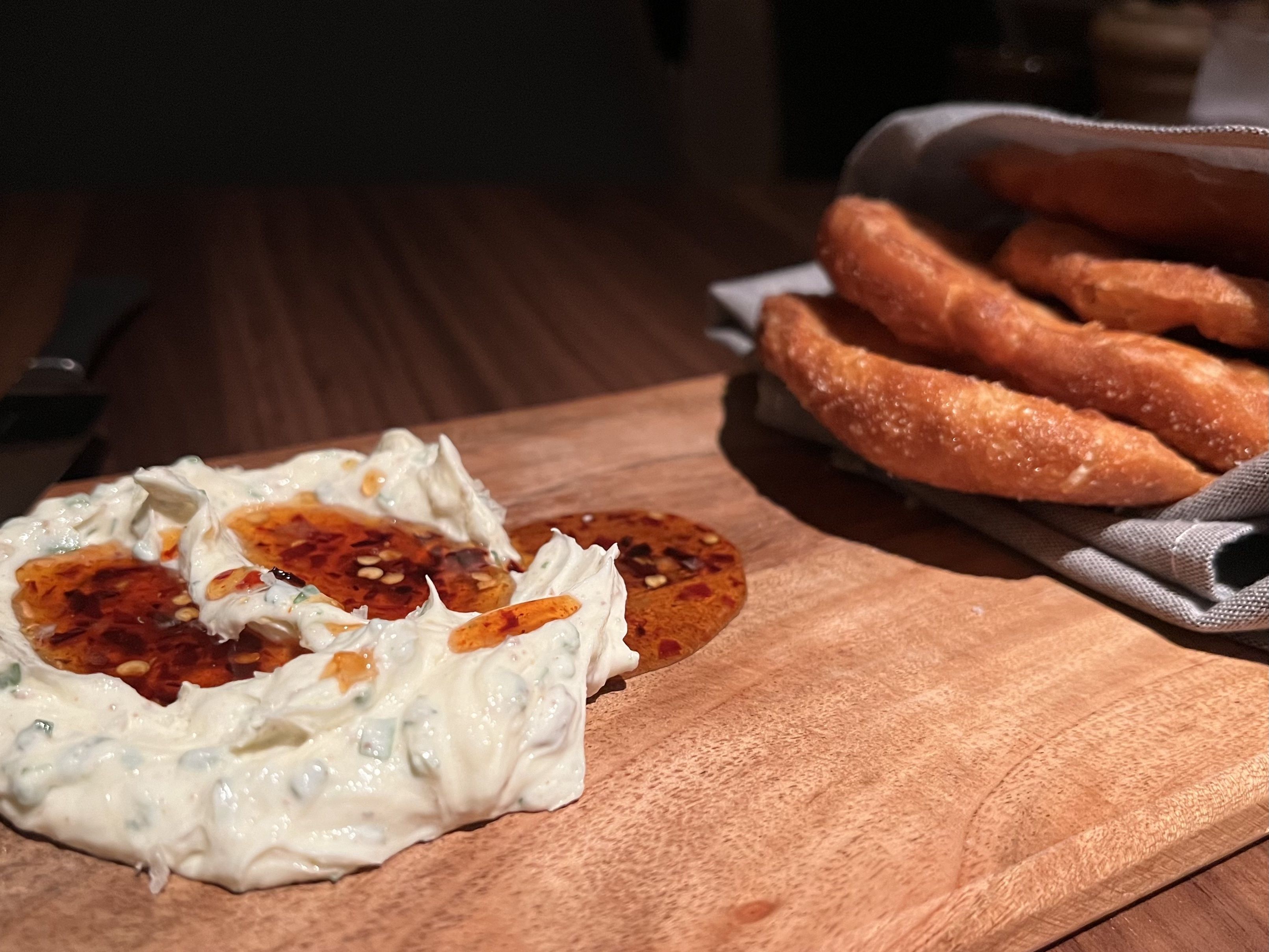 A photo high in contrast shows a spread of whipped butter with honey and a stack of fried dough.