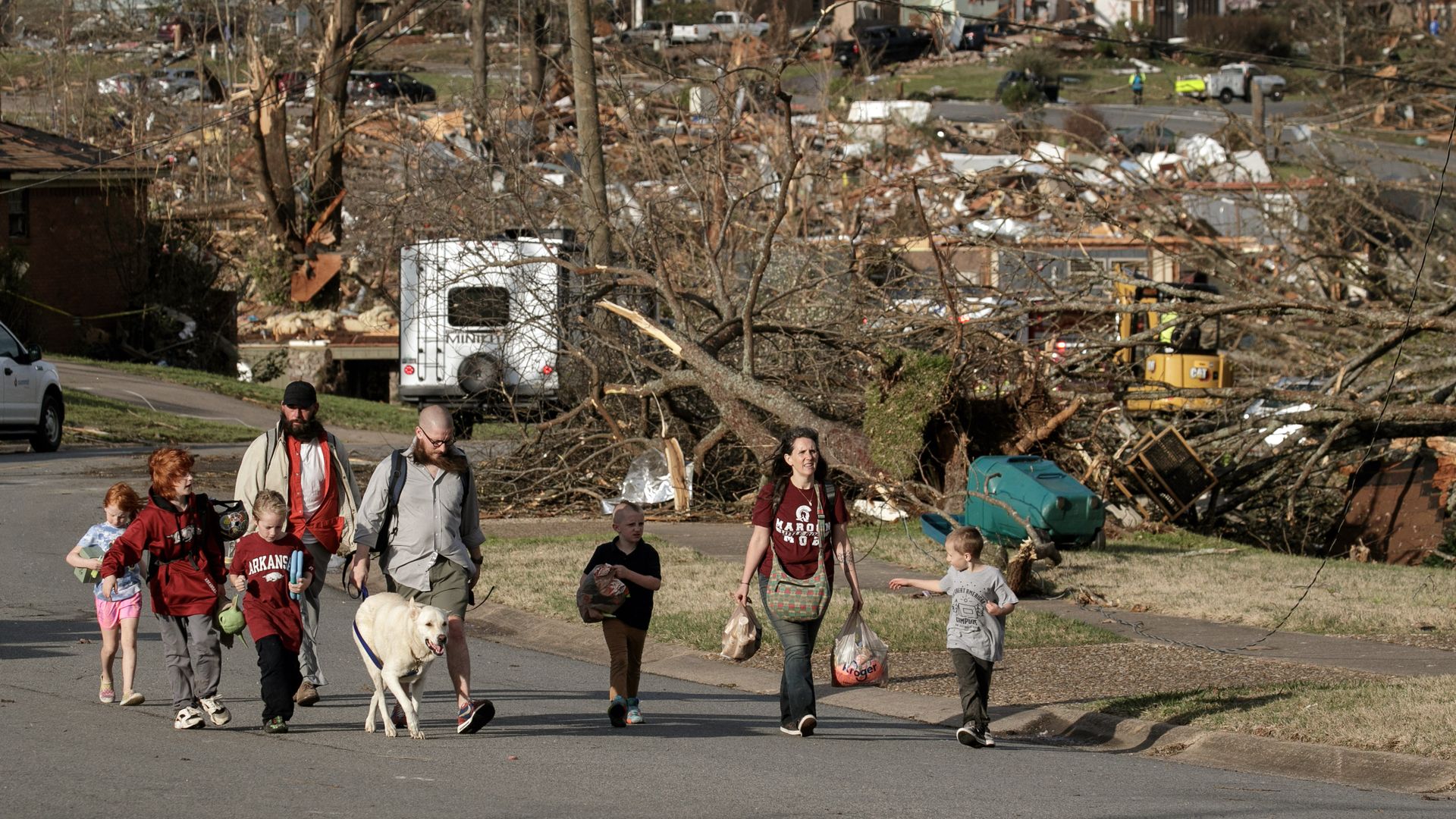 A family walks among tornado destruction in a North Little Rock, Arkansas neighborhood after a tornado struck on March 31.