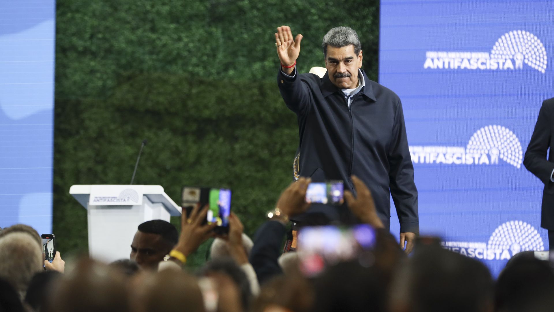 Venezuela President Nicolás Maduro waves at a crowd while on a stage