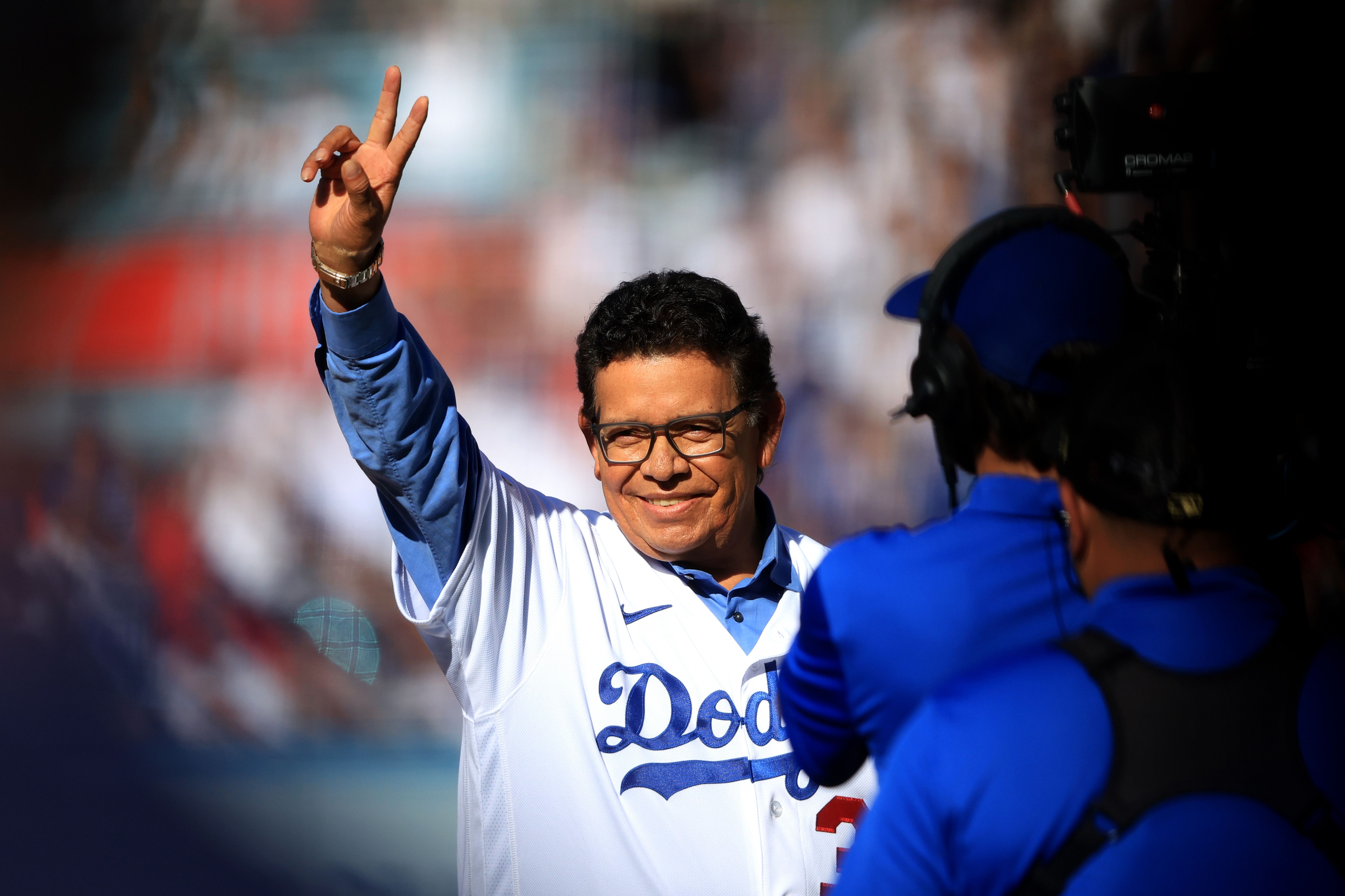 Fernando Valenzuela holds up the peace sign and smiles as the sun beams on his face.