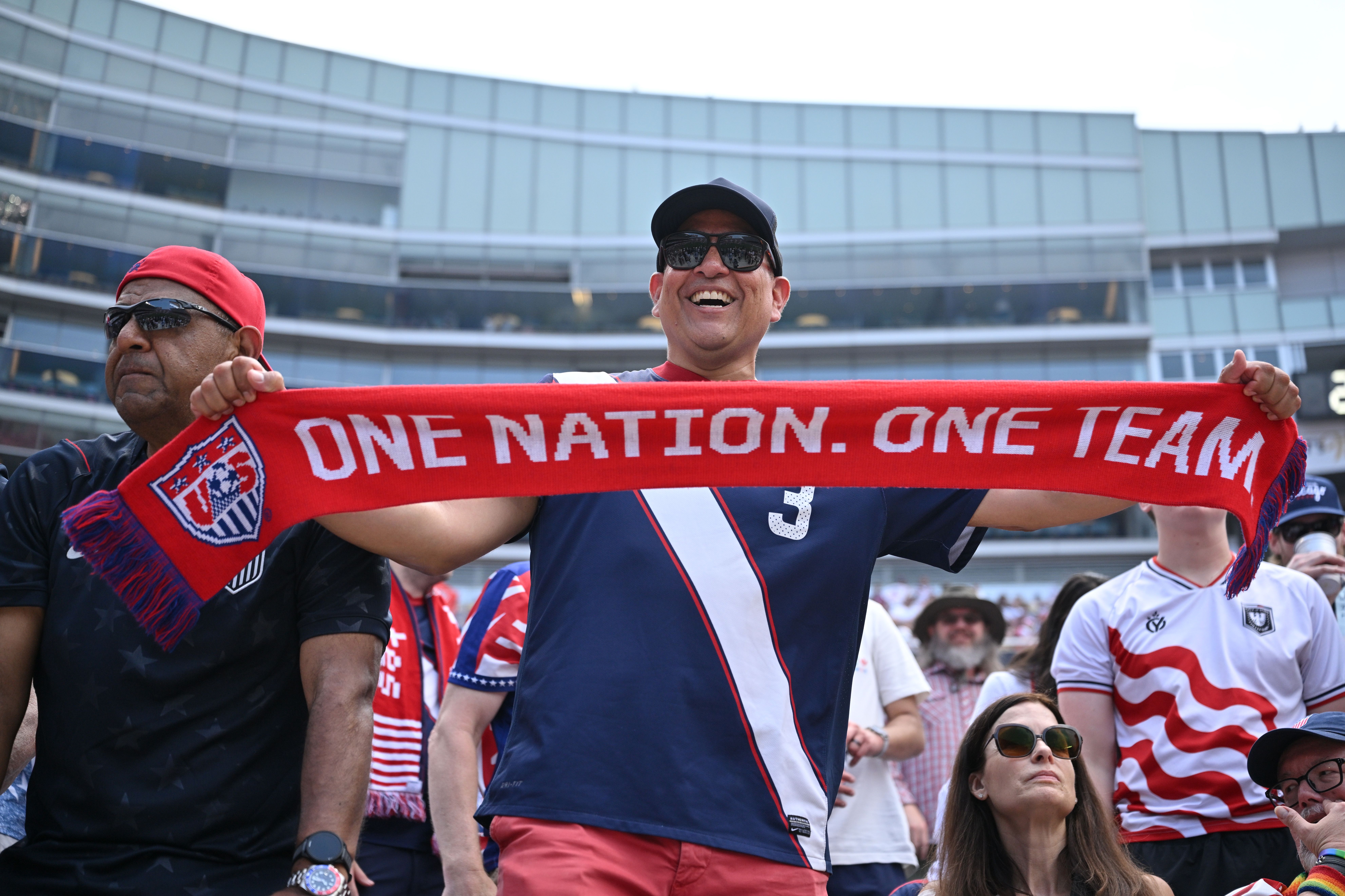 A USA fan holds up a scarf that reads "One nation. One team."