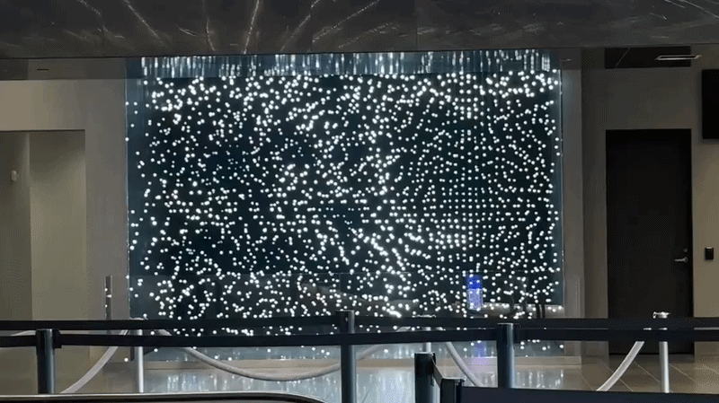 A gif of a hanging LED lights twinkling in an art exhibit. The lights flash to show a football player running across the field for a touchdown.