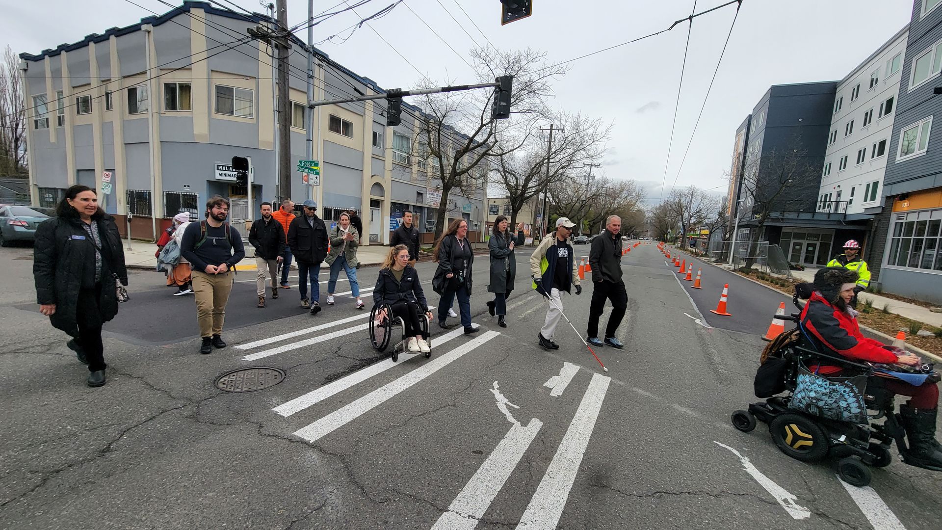 People walking and rolling across an intersection in a Seattle neighborhood. 