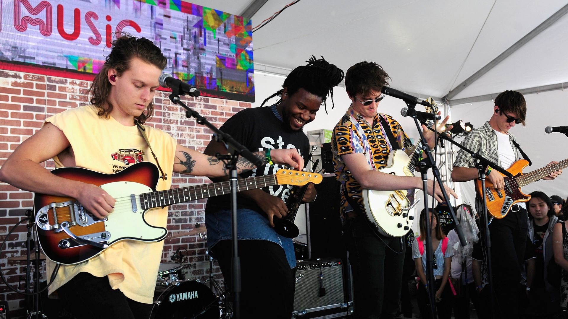 Four men playing the guitar on a stage.