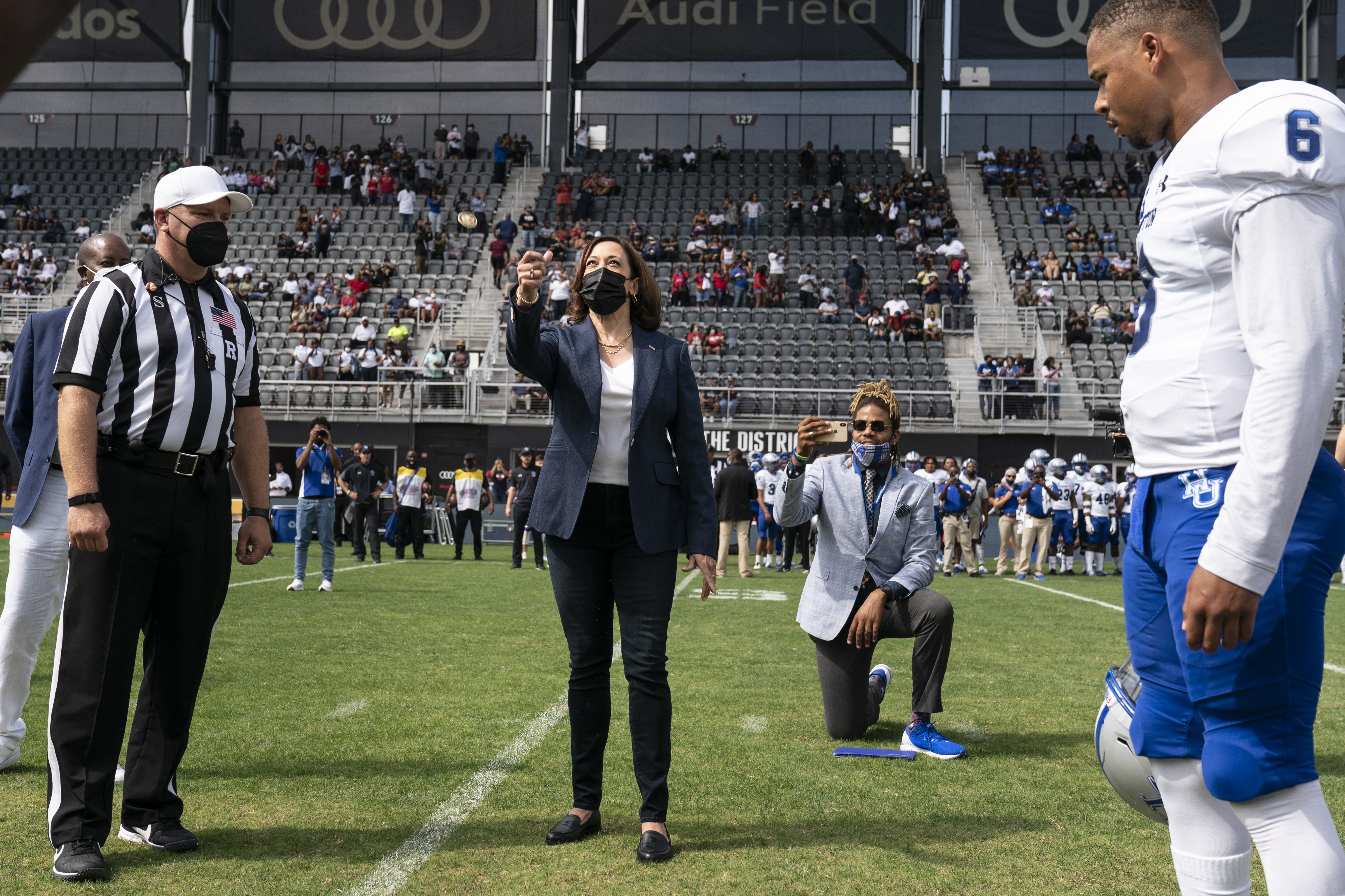 ice President Kamala Harris, center, flips a coin ahead of the Howard University and Hampton University football game at Audi Field in Washington, D.C
