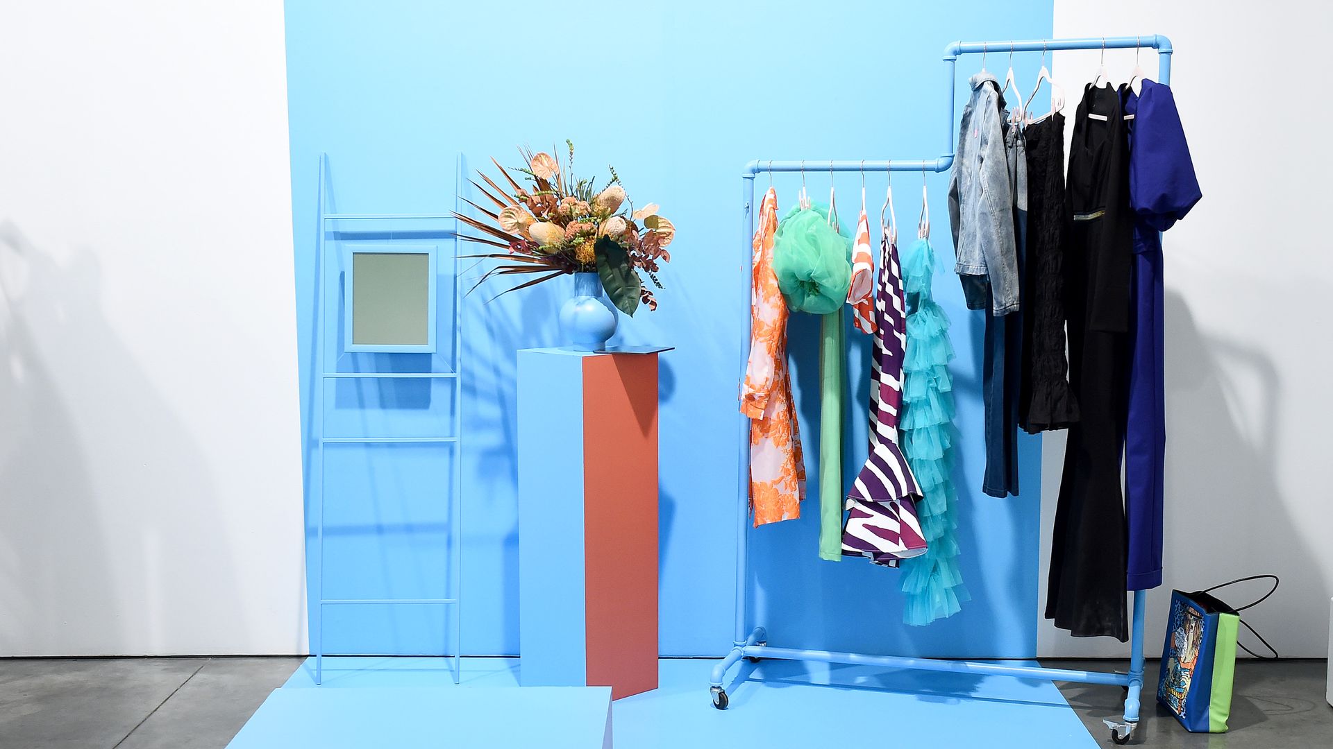 A full clothing rack in front of a blue backdrop.