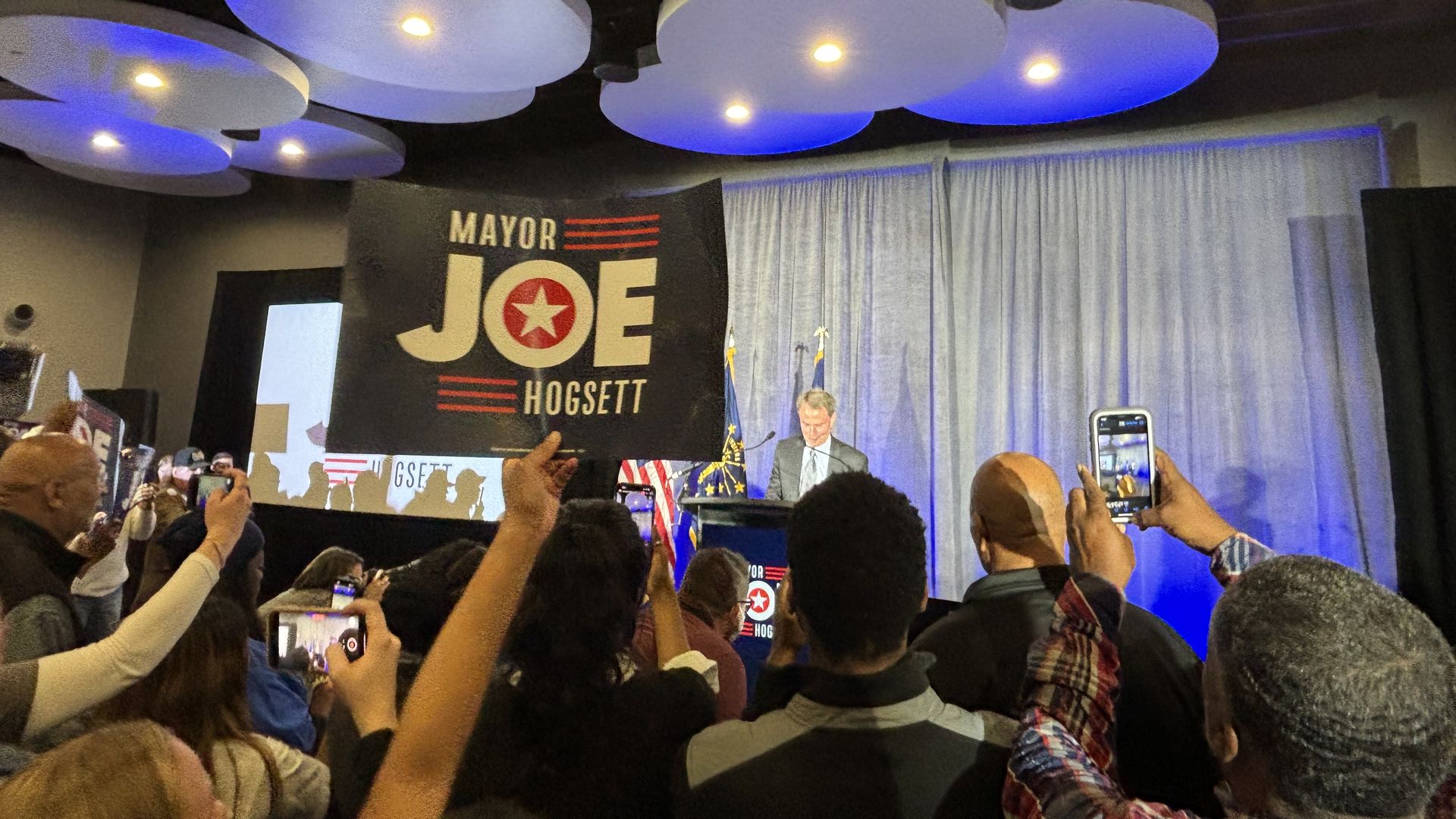 A supper holds a "Mayor Joe Hogsett" sign up as Hogsett delivers a victory speech after winning re-election to a third term.