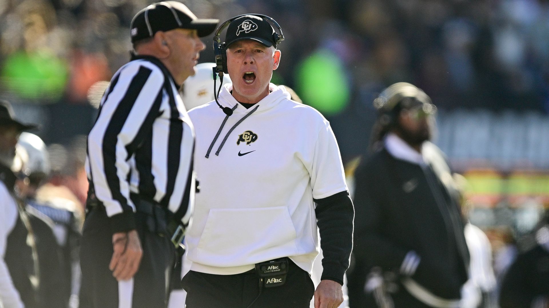 Pat Shurmer in white hoodie with CU Buffaloes logo yelling at a referee in black-and-white striped uniform during a game.
