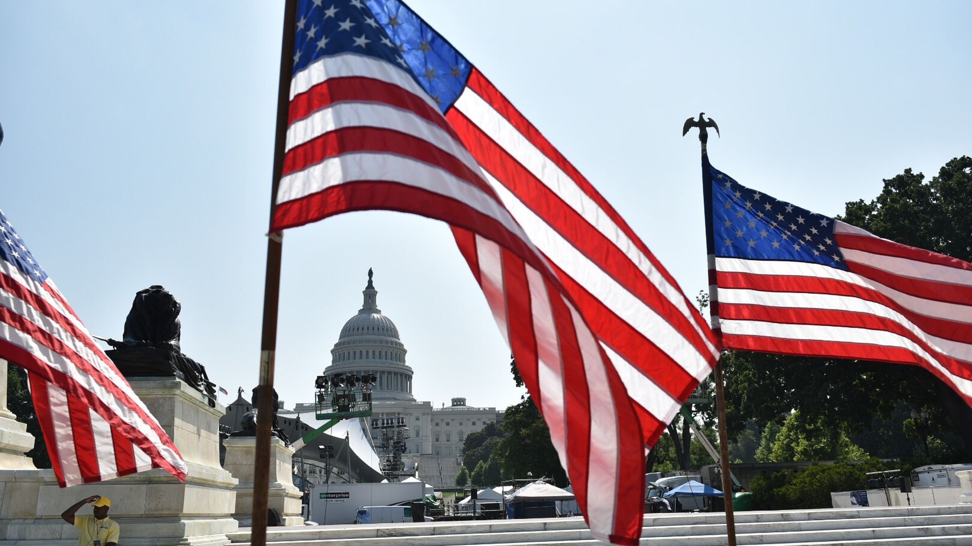 U.S. flags fly in front of the Capitol building.