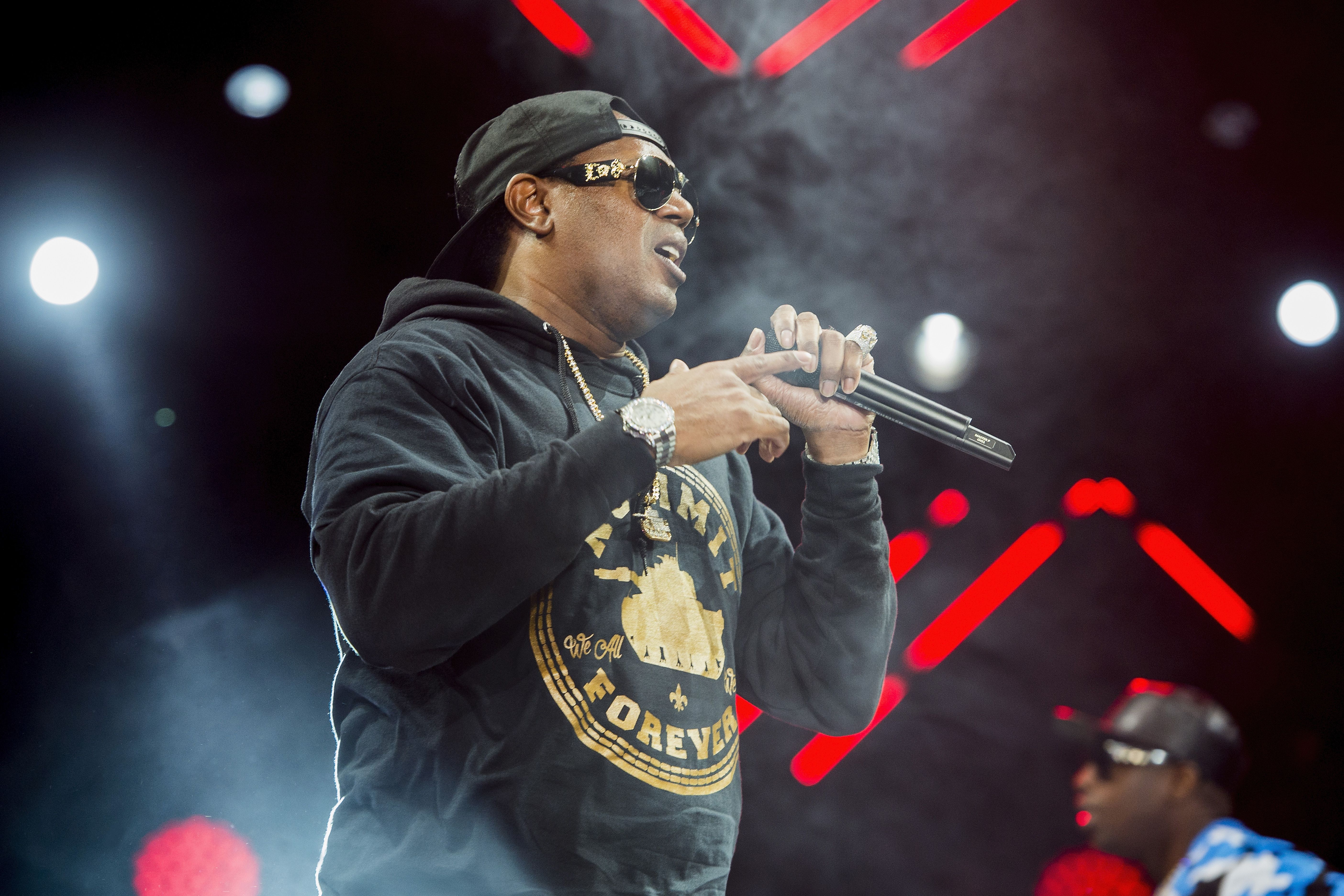 Master P performs onstage, holding a microphone.