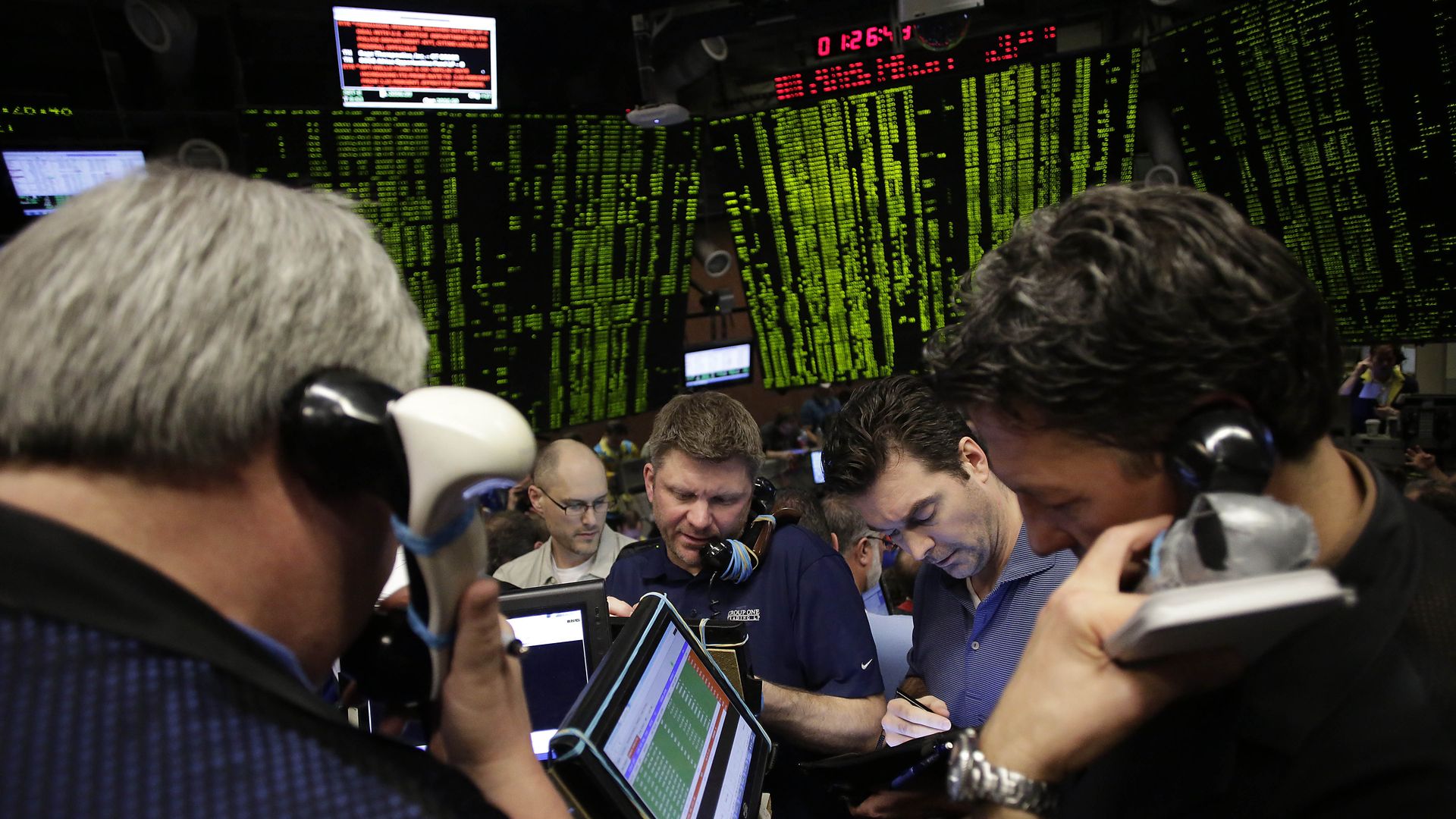 In this image, traders work at the stock market floor and take calls.