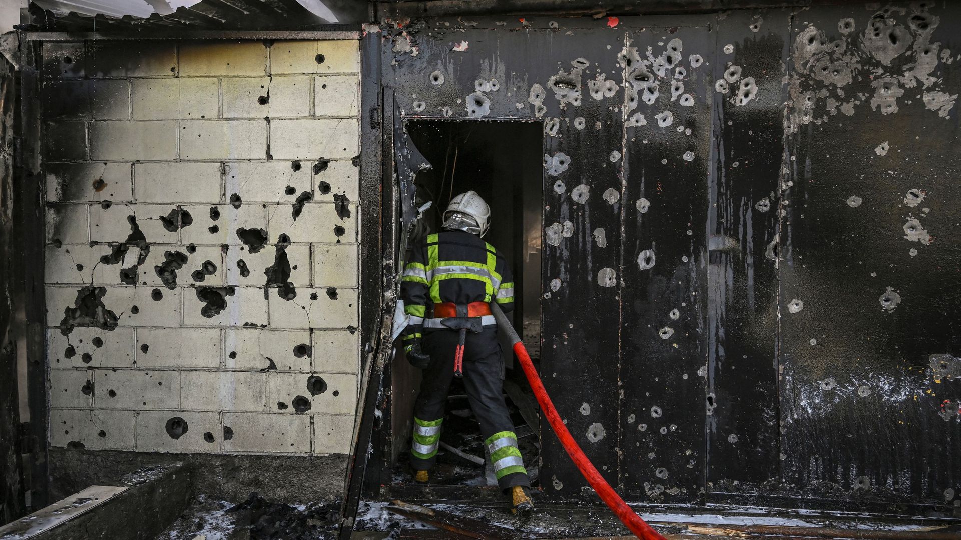 A firefighter enters a house to extinguish a fire after shelling on the 17th day of the Russian invasion of Ukraine, in Kyiv on March 12, 2022. 