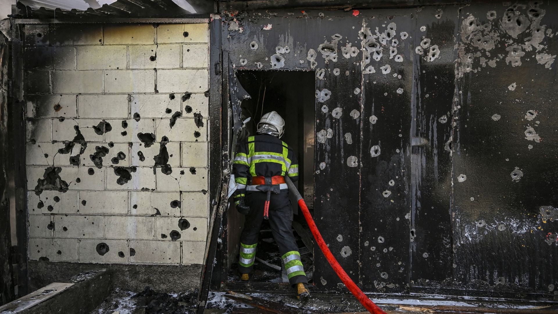 A firefighter enters a house to extinguish a fire after shelling on the 17th day of the Russian invasion of Ukraine, in Kyiv on March 12, 2022. 