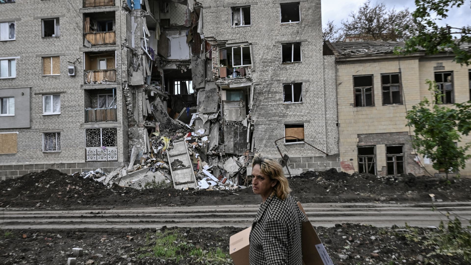 A woman walks by a destroyed apartment building in Bakhmut in the Donbas region
