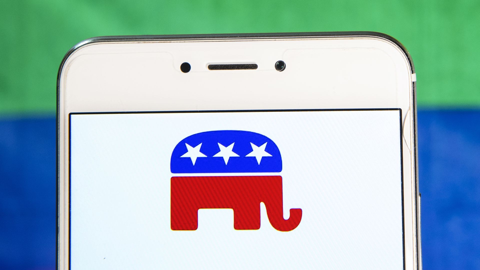 In this photo illustration, the Republican Party icon is seen displayed on an Android mobile device with a LGTB rainbow in the background. 
