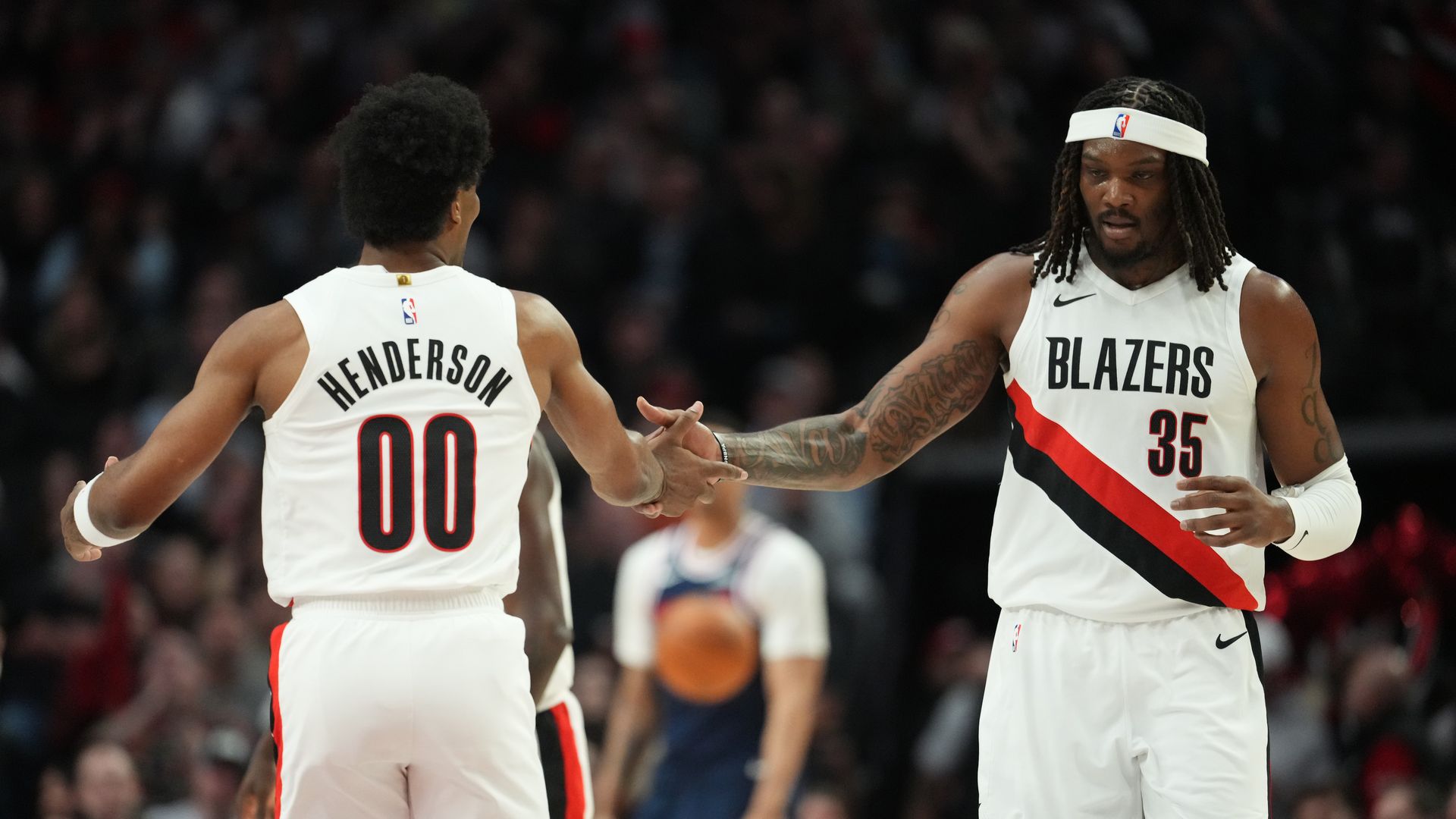 Two Portland Trail Blazers players shake hands on the court: Henderson #00 on the left and #35 with a headband on the right, crowd in the background.