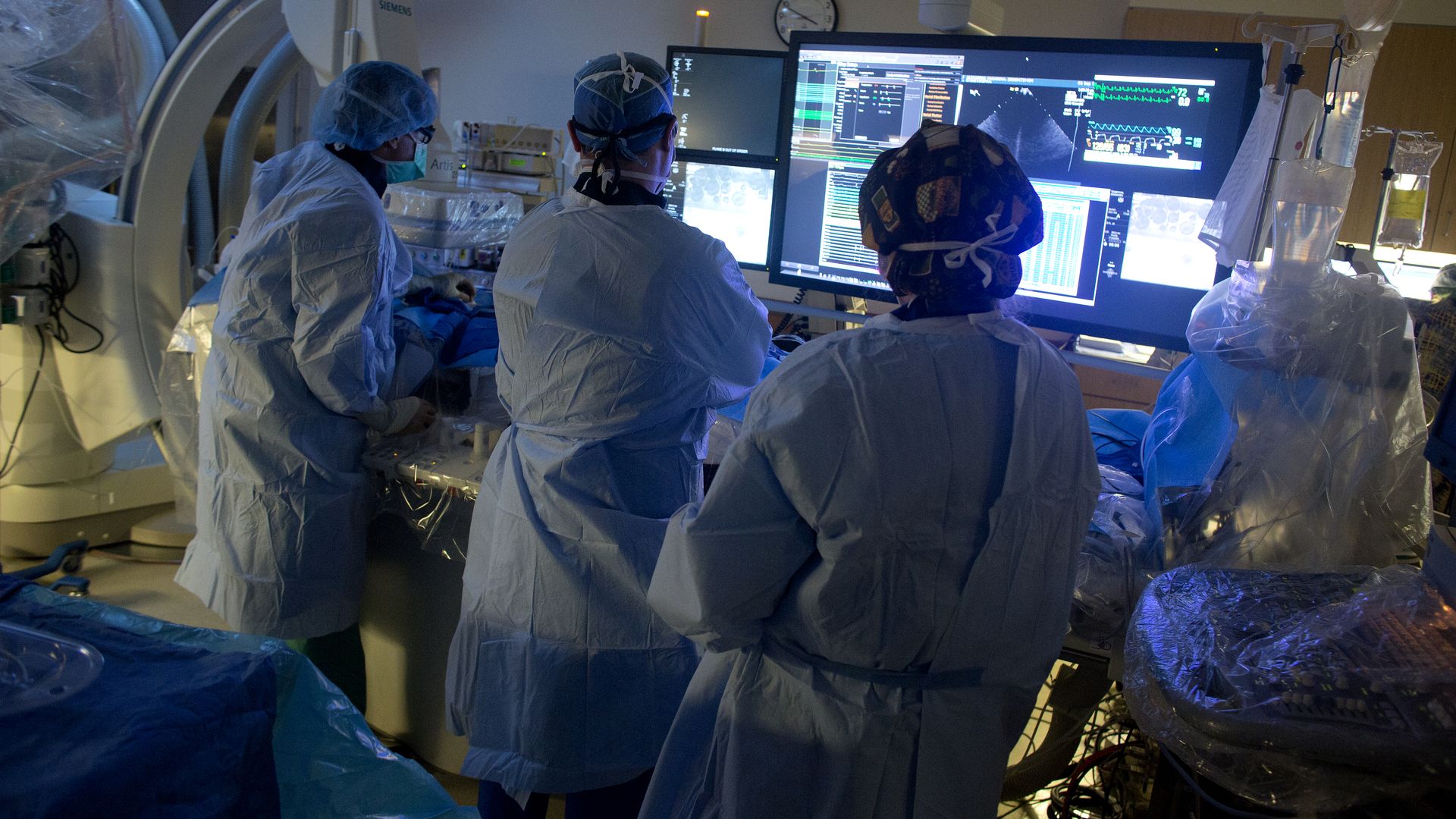Doctors in hospital scrubs look at a monitor