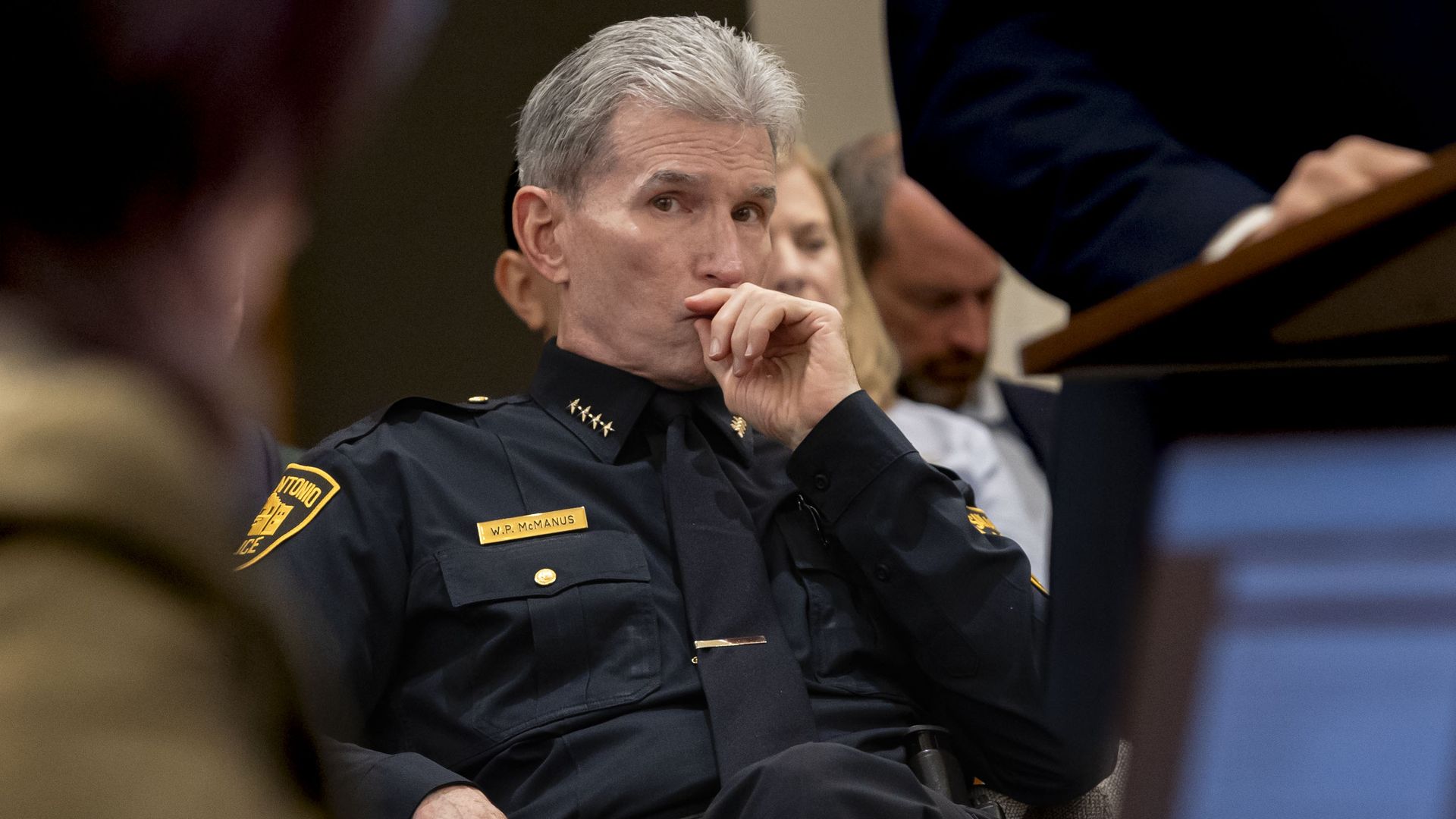 San Antonio Police Chief William McManus as seen at a City Council committee meeting in September 2024. He is dressed in uniform and making a contemplative face while holding his hand to his mouth.